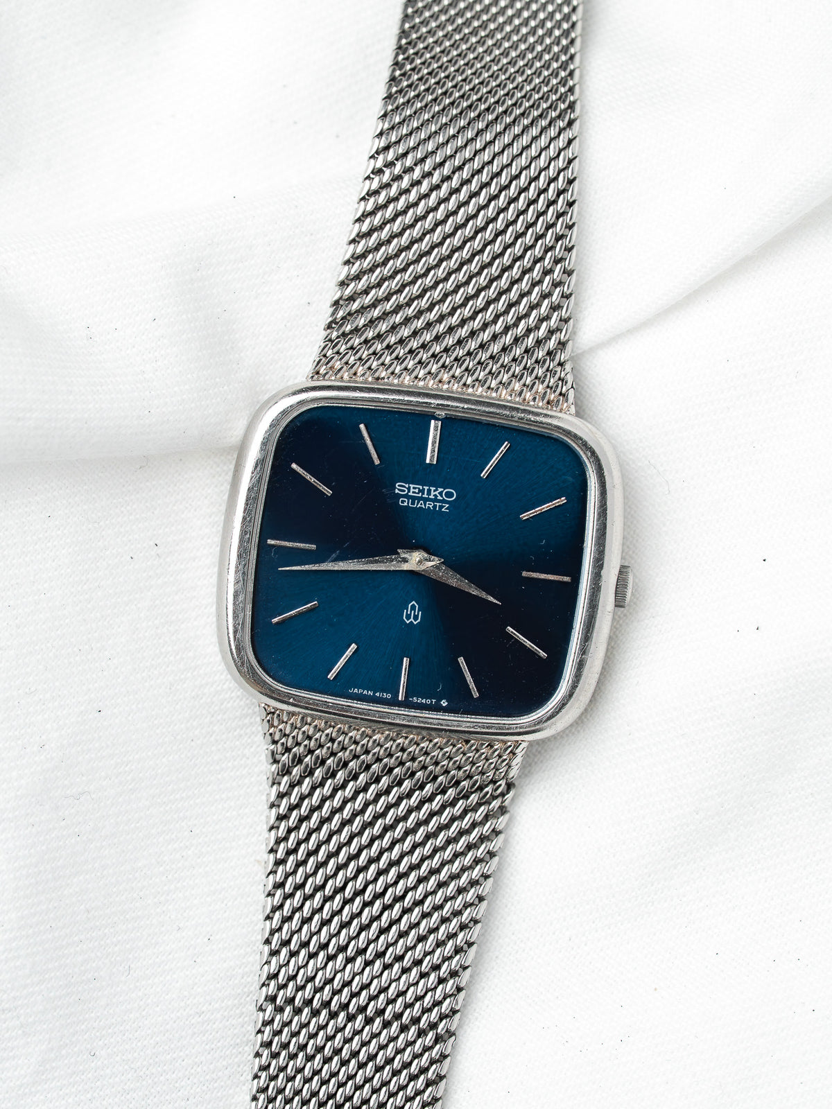 Seiko Quartz vintage watch with blue dial, silver mesh bracelet, square case on white background