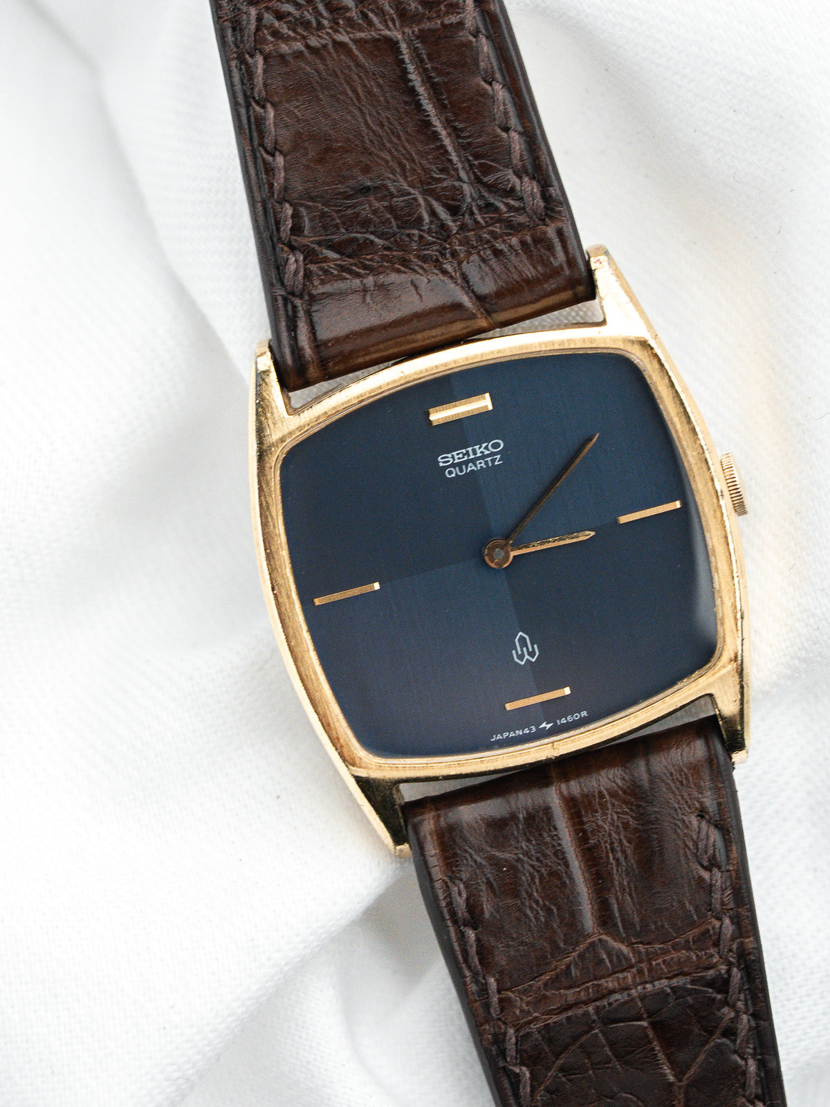 Montre Seiko Quartz vintage au cadran bleu et bracelet en cuir marron.