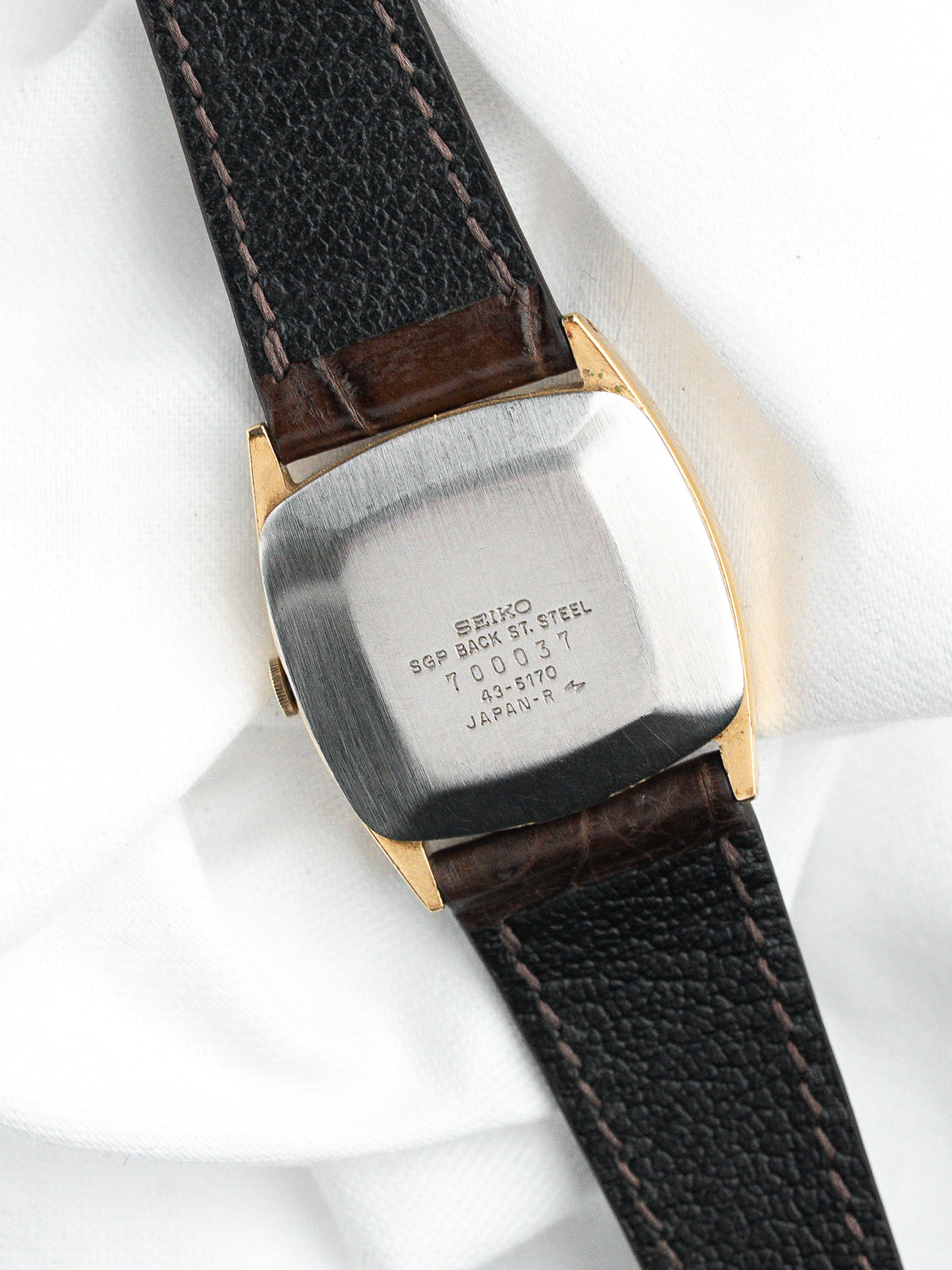 Dos d'une montre Seiko vintage en acier avec bracelet en cuir noir grainé.