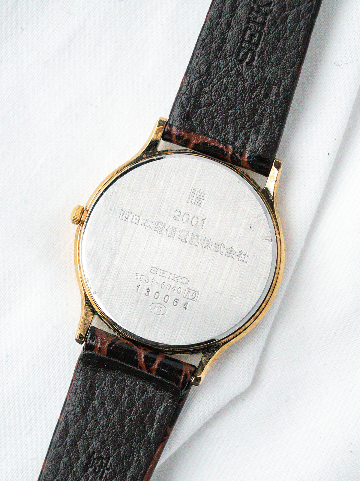 Seiko watch back with gold case, brown leather strap, engraved details