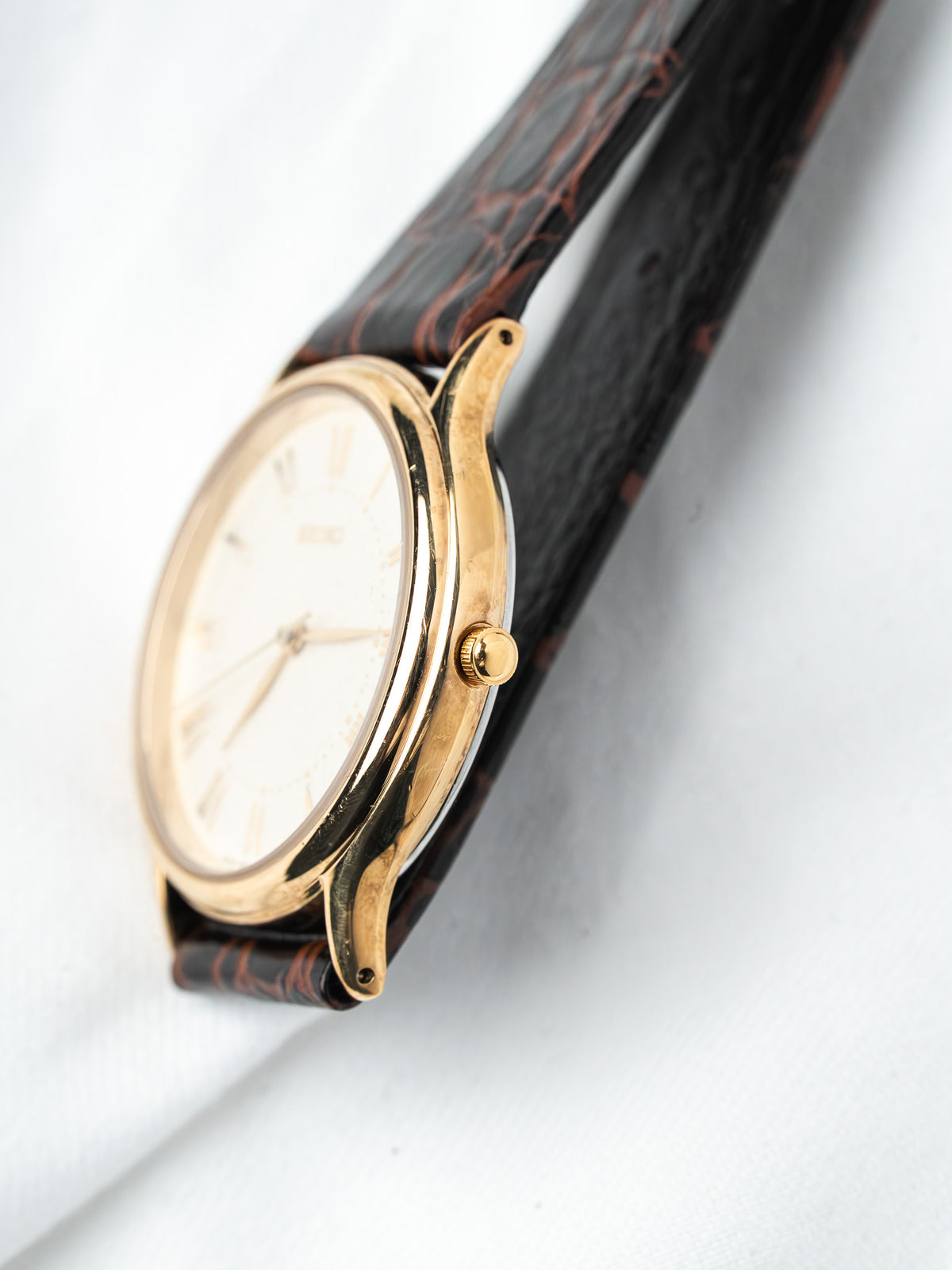 Vintage Omega watch with gold case, white dial, and brown leather strap