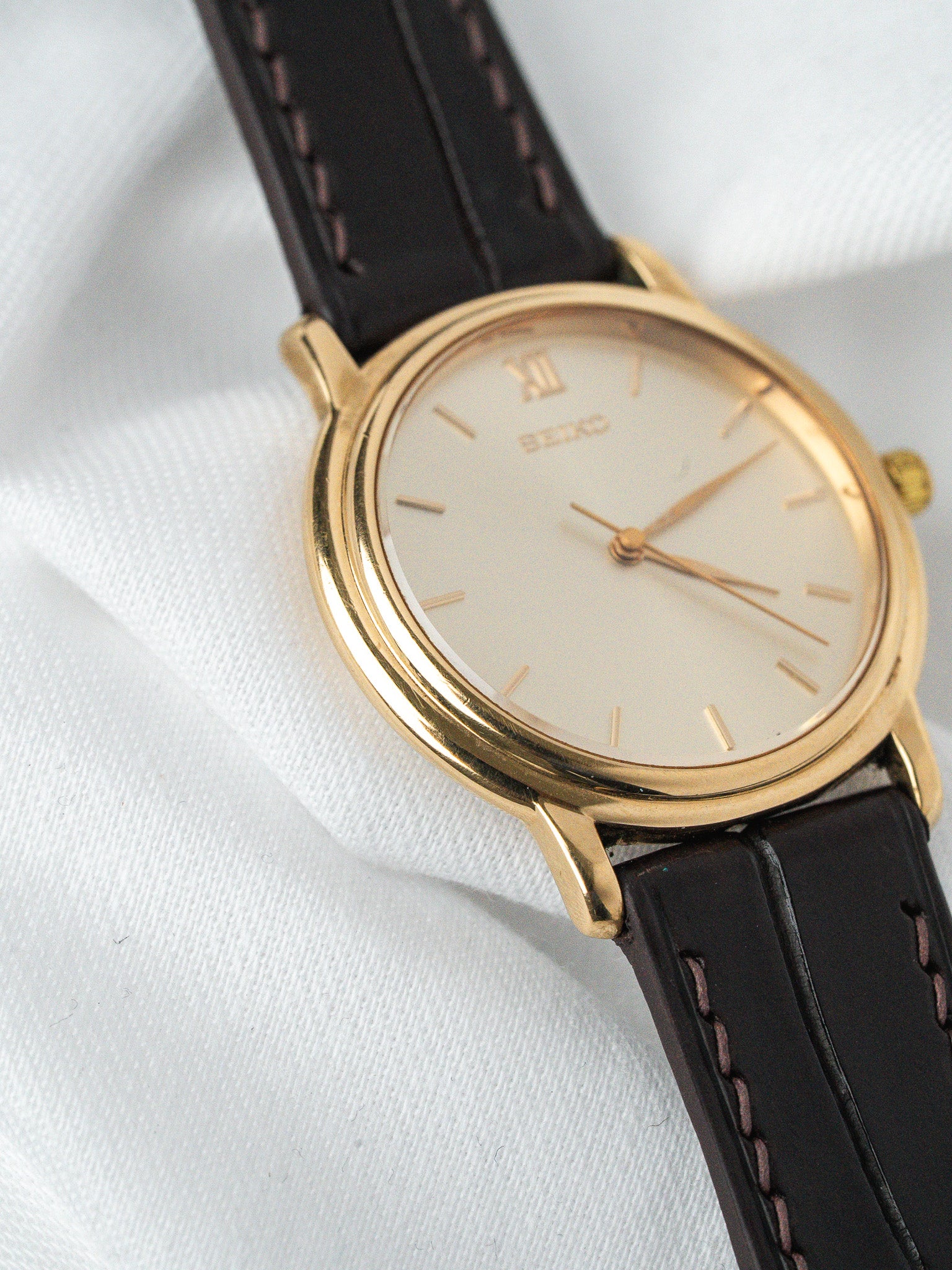 Seiko vintage watch with gold case, cream dial, and black leather strap