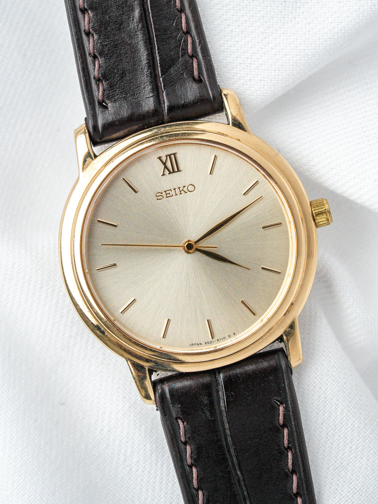 Seiko vintage watch with gold case, silver dial, Roman XII, black leather strap