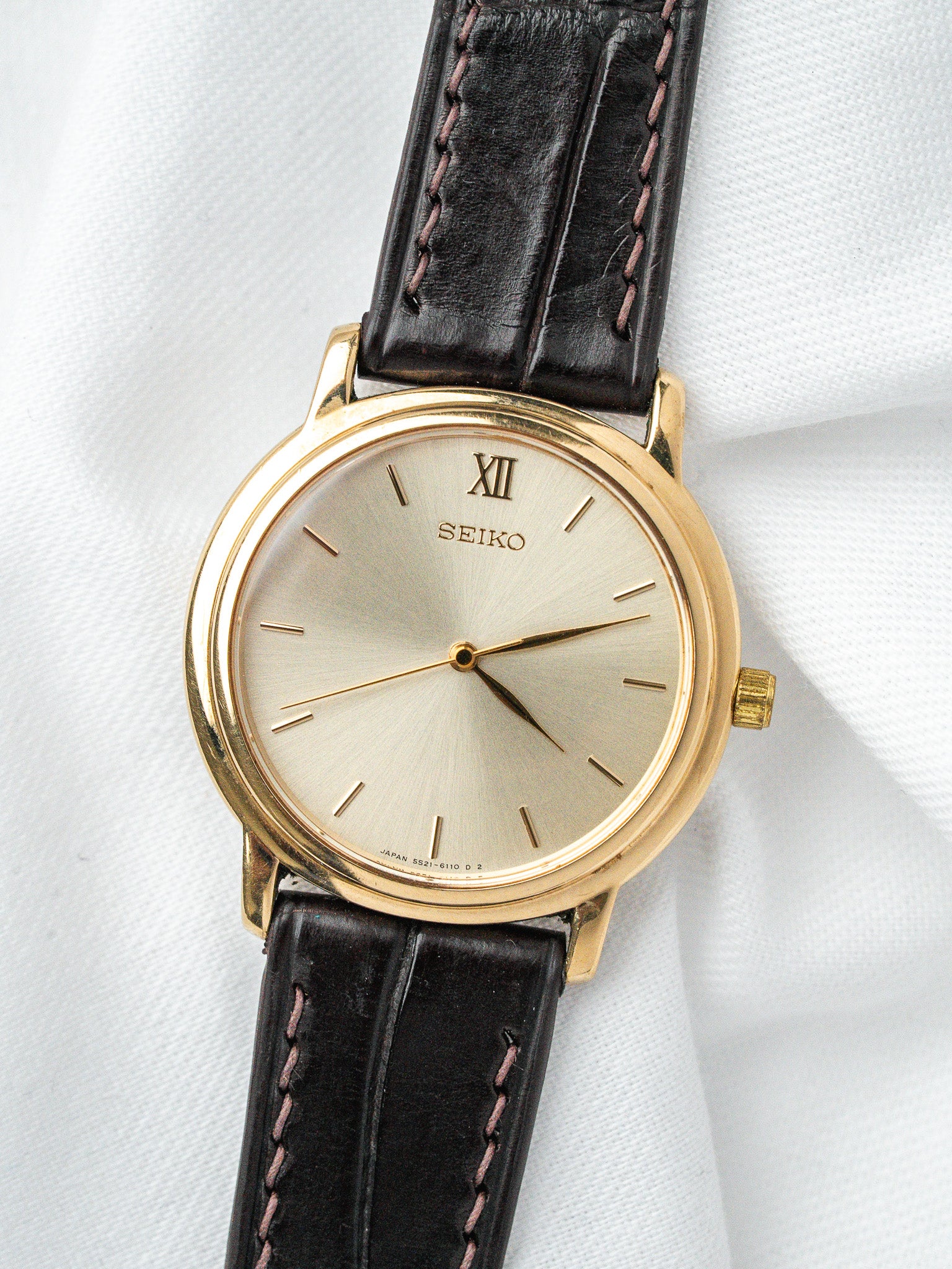 Seiko vintage watch with gold case, silver dial, Roman XII, black leather strap