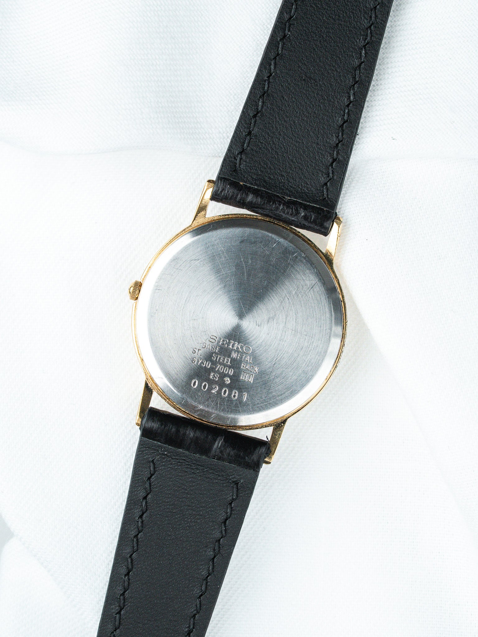 Seiko vintage watch with gold case, black leather strap, steel back on white
