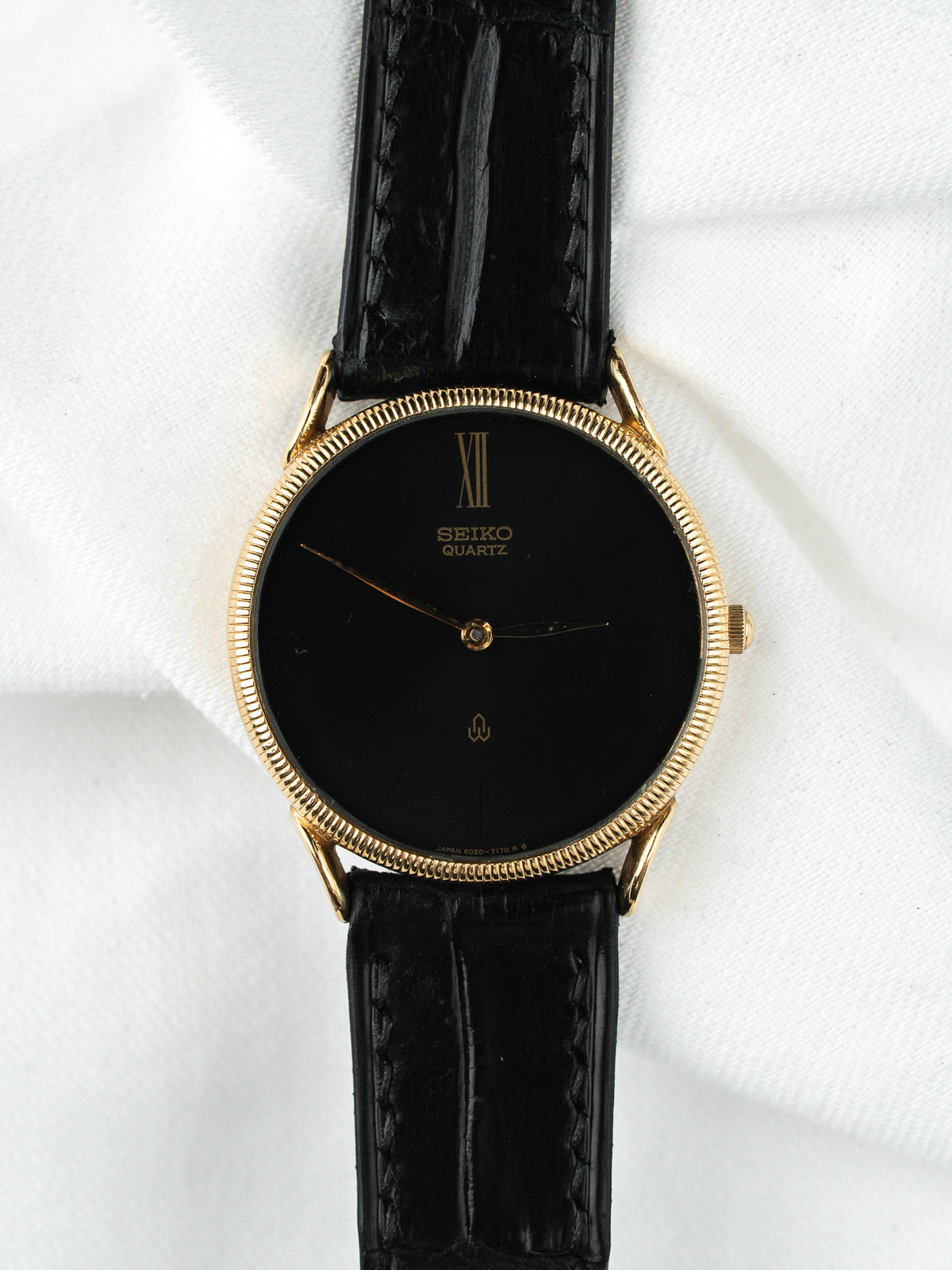 Montre Seiko Quartz vintage, boîtier doré, cadran noir et bracelet en cuir noir