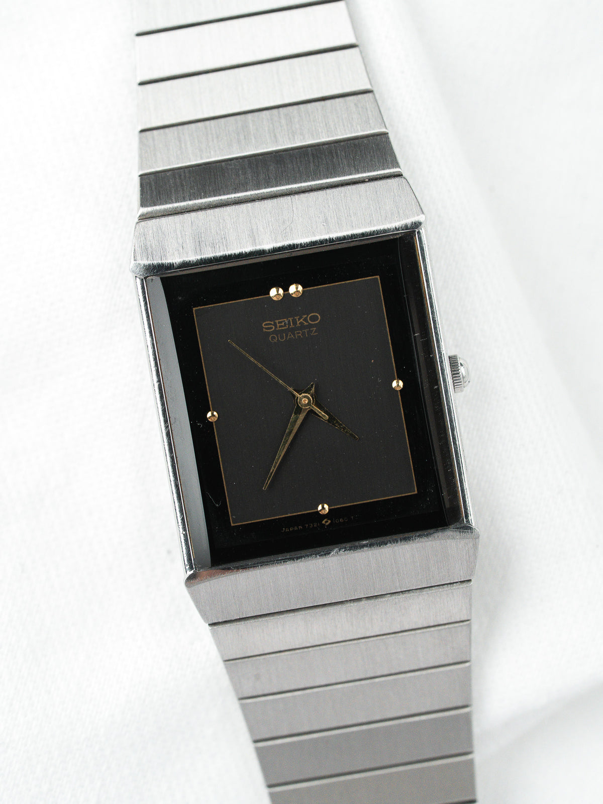 Montre Seiko Quartz vintage avec cadran noir carré et bracelet en acier inoxydable.