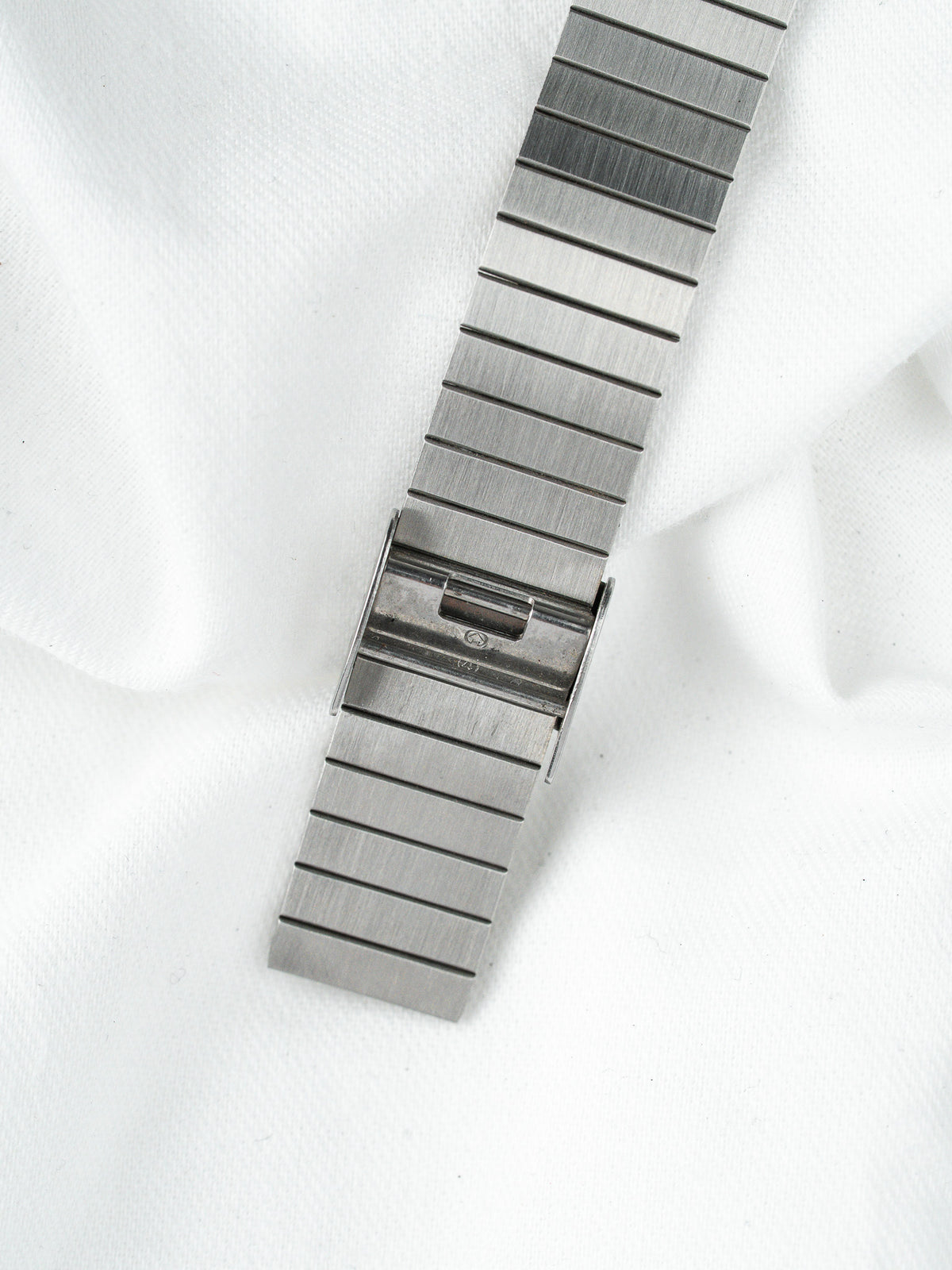 Bracelet de montre en acier inoxydable argenté avec fermoir déployant sur fond blanc.