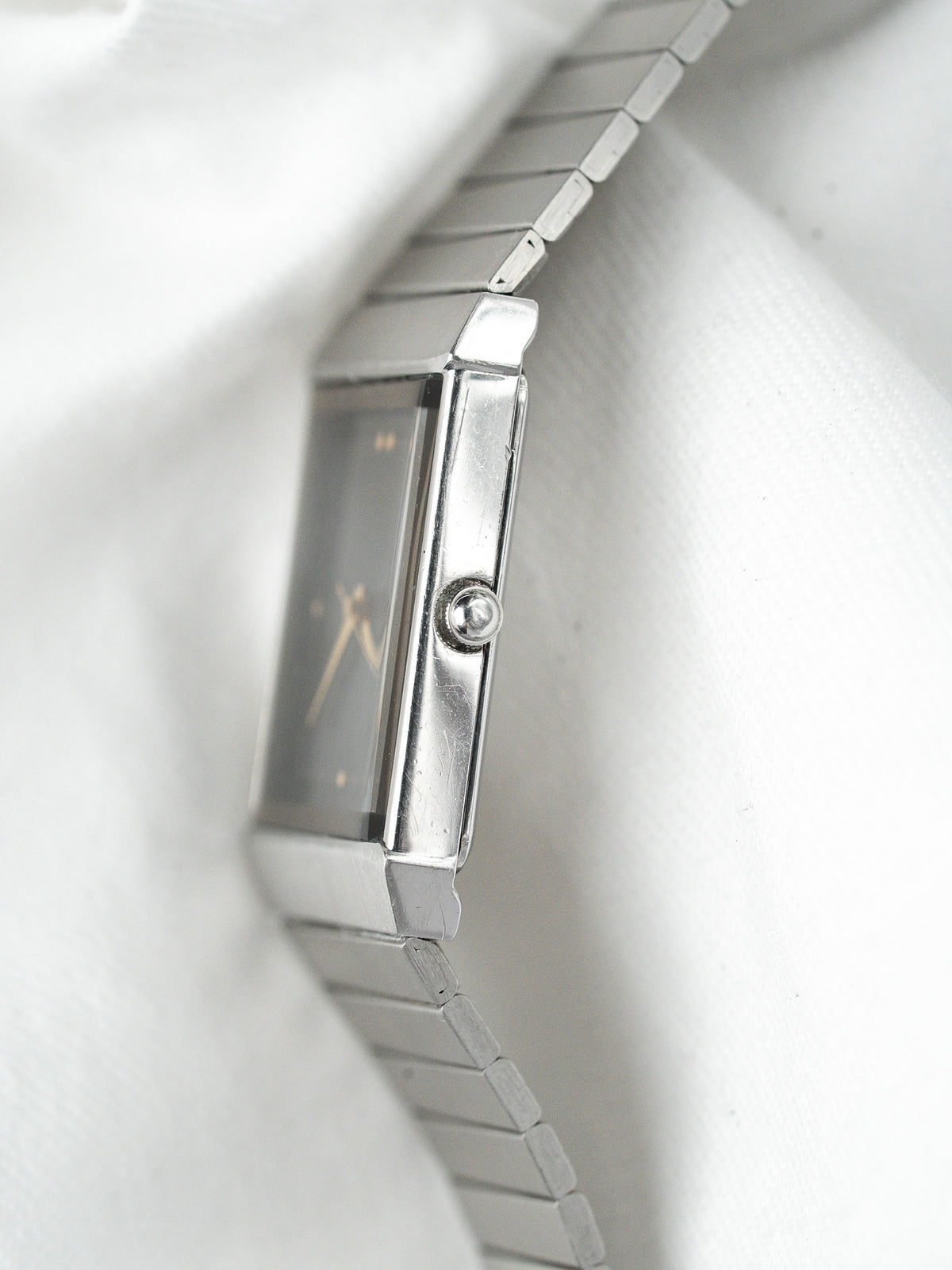 Vue de profil d'une montre vintage rectangulaire en acier avec bracelet à maillons.