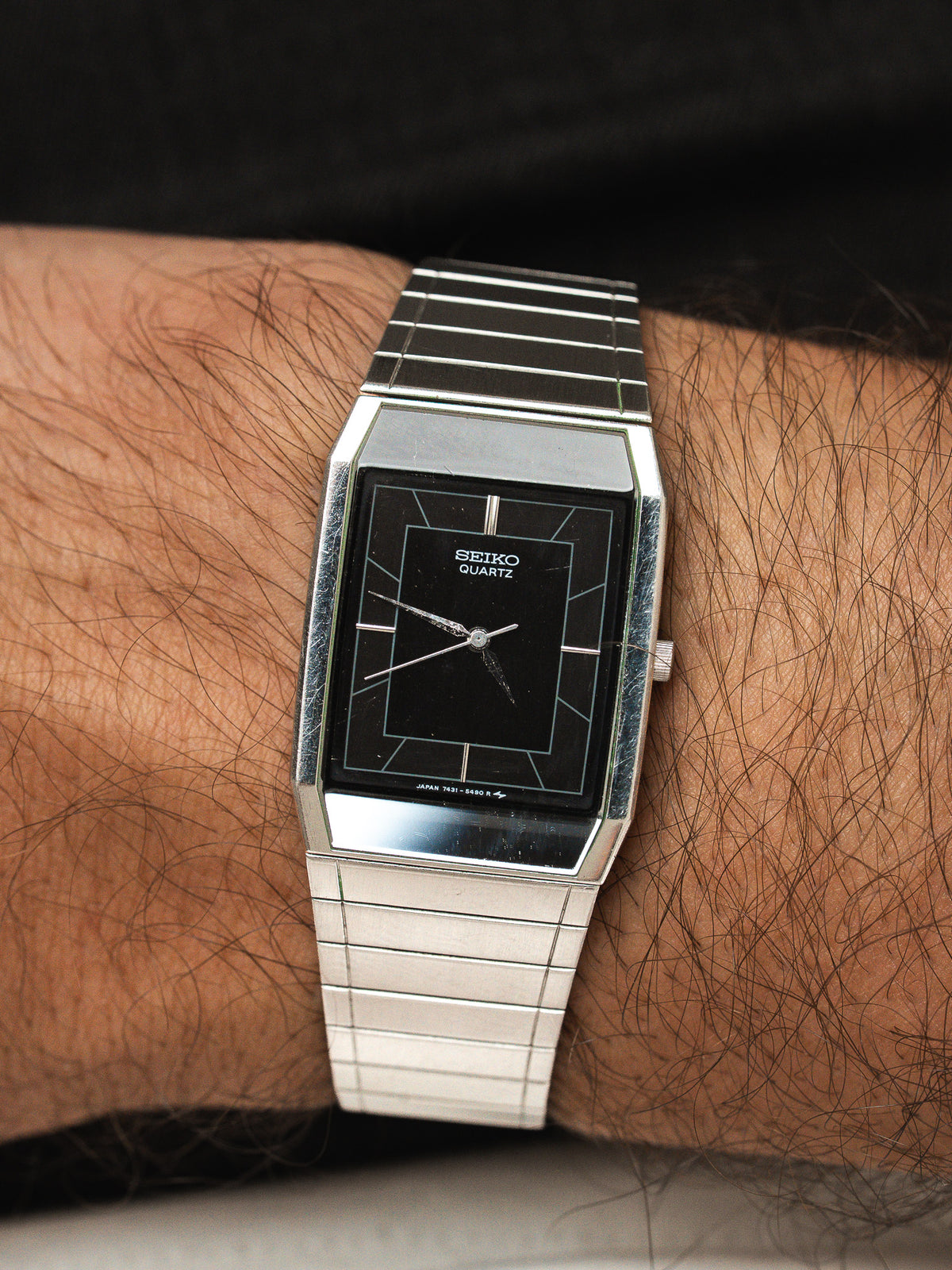 Montre Seiko Quartz vintage avec cadran noir et bracelet en acier argenté.