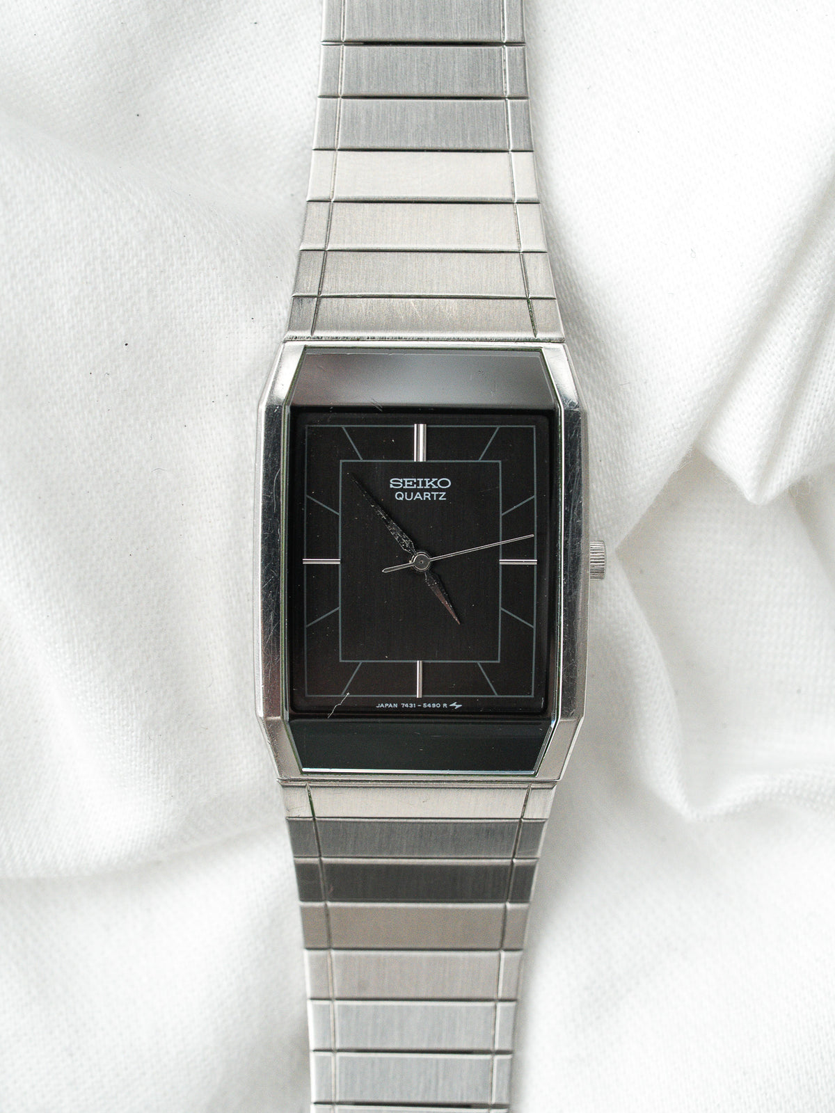 Montre Seiko Quartz vintage avec cadran noir rectangulaire et bracelet en acier argenté.