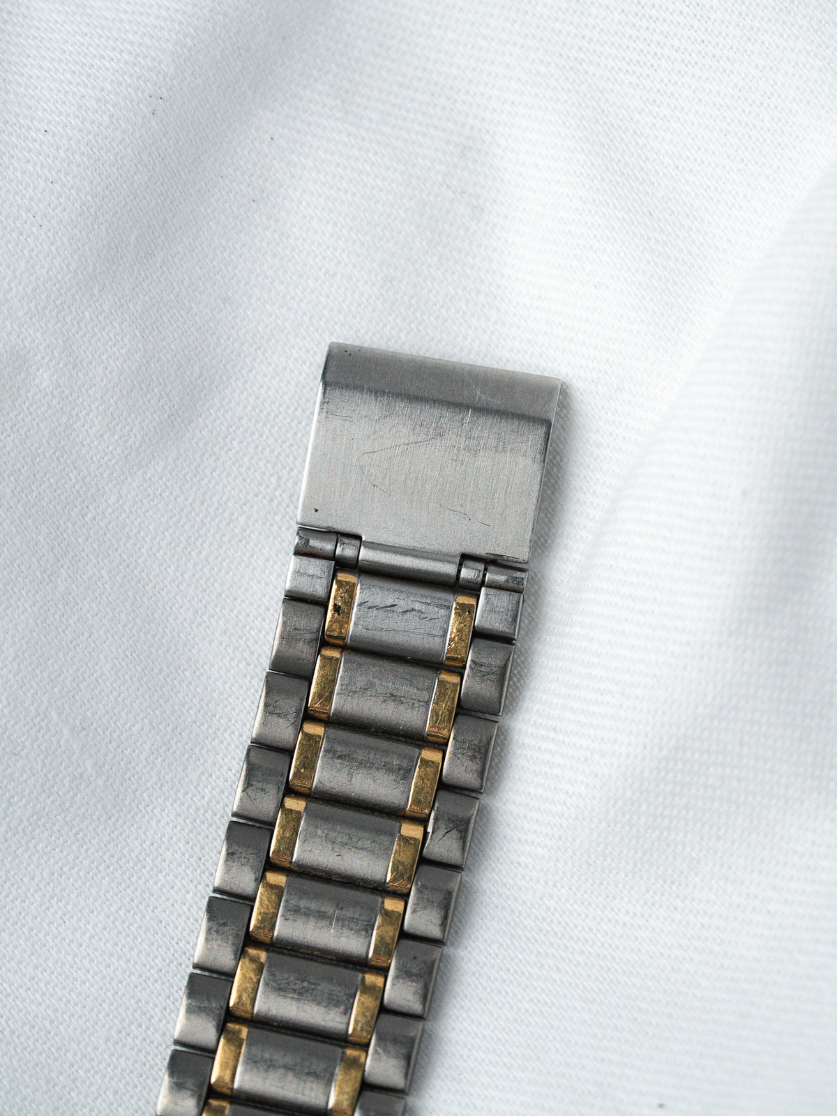 Vintage two-tone metal bracelet with brushed silver and gold accents on white fabric