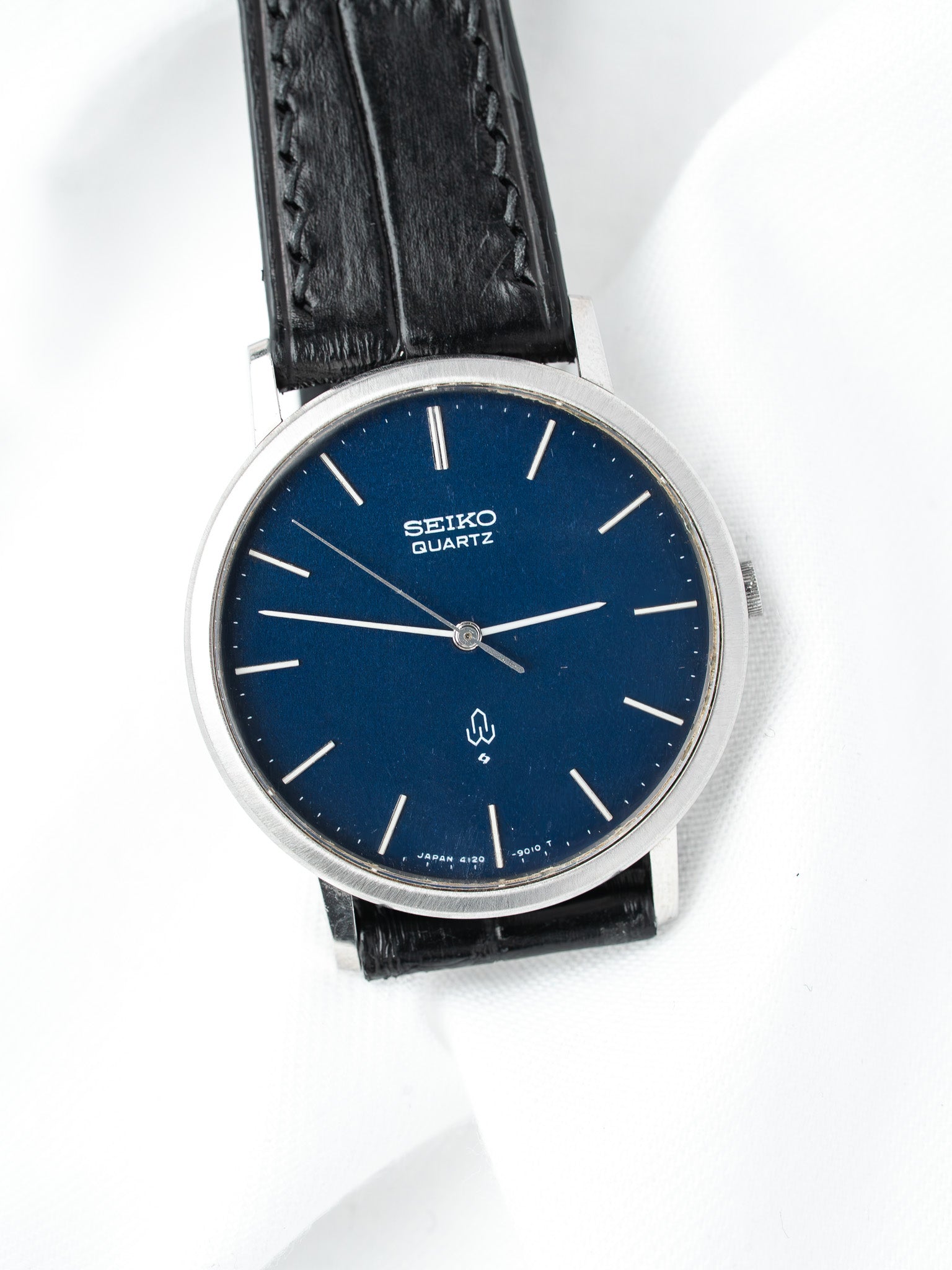 Seiko Quartz vintage watch with blue dial, silver hands, black leather strap on white background