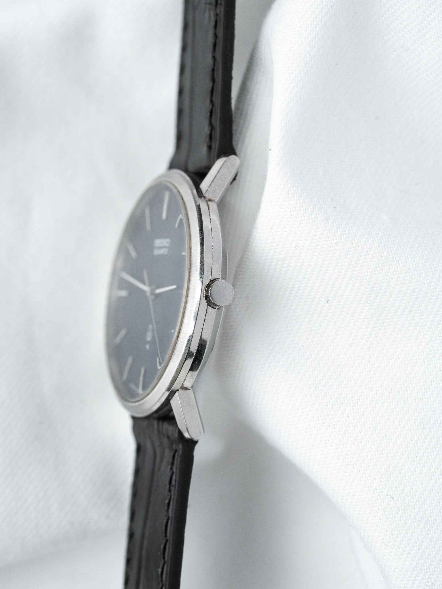 Seiko vintage watch with grey dial, stainless steel case, black leather strap on white fabric