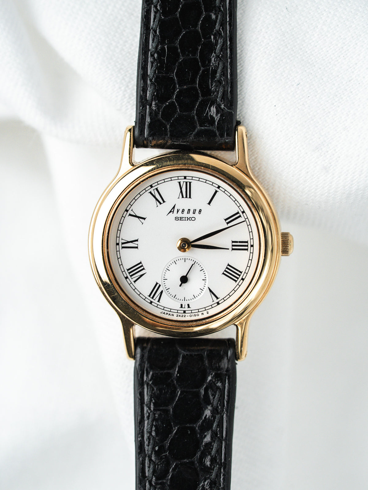 Montre Seiko Avenue vintage, boîtier rond doré, cadran blanc et bracelet cuir noir