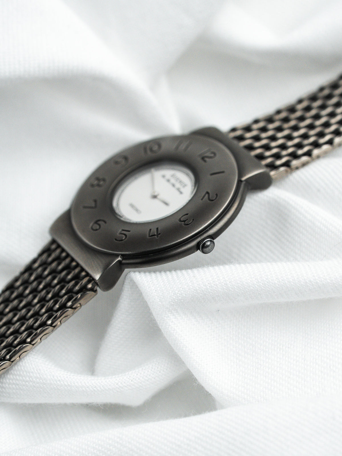 Montre vintage au boîtier ovale gris foncé, cadran blanc et bracelet maille milanaise
