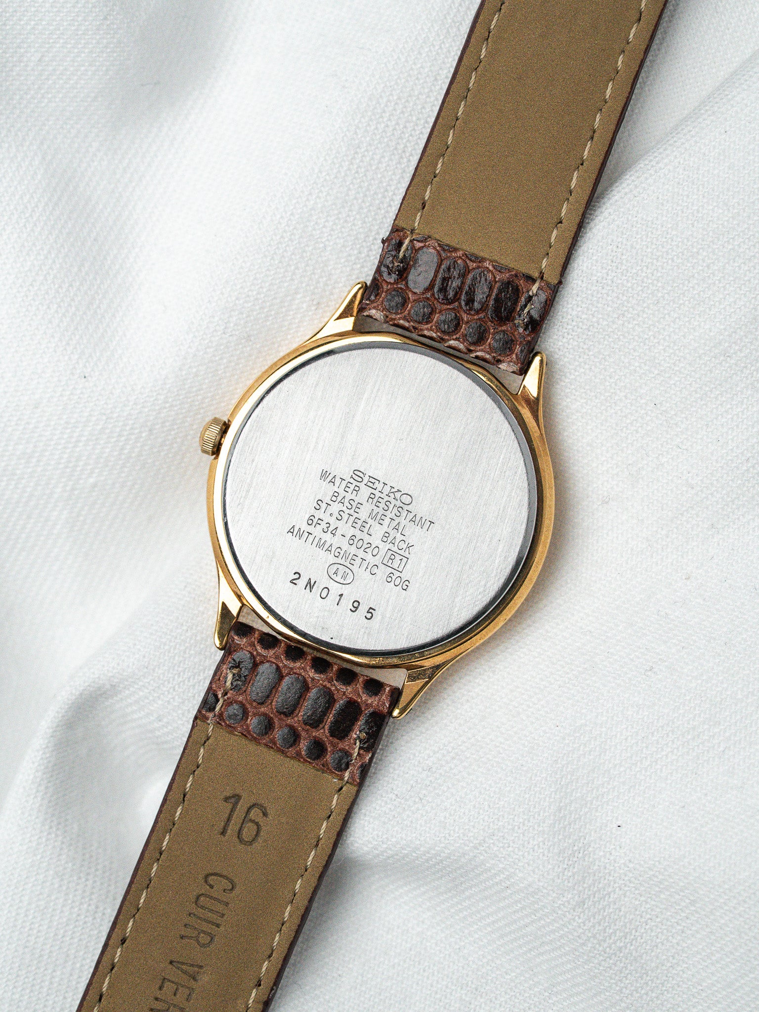 Seiko vintage watch with gold case, brown leather strap, and stainless steel back