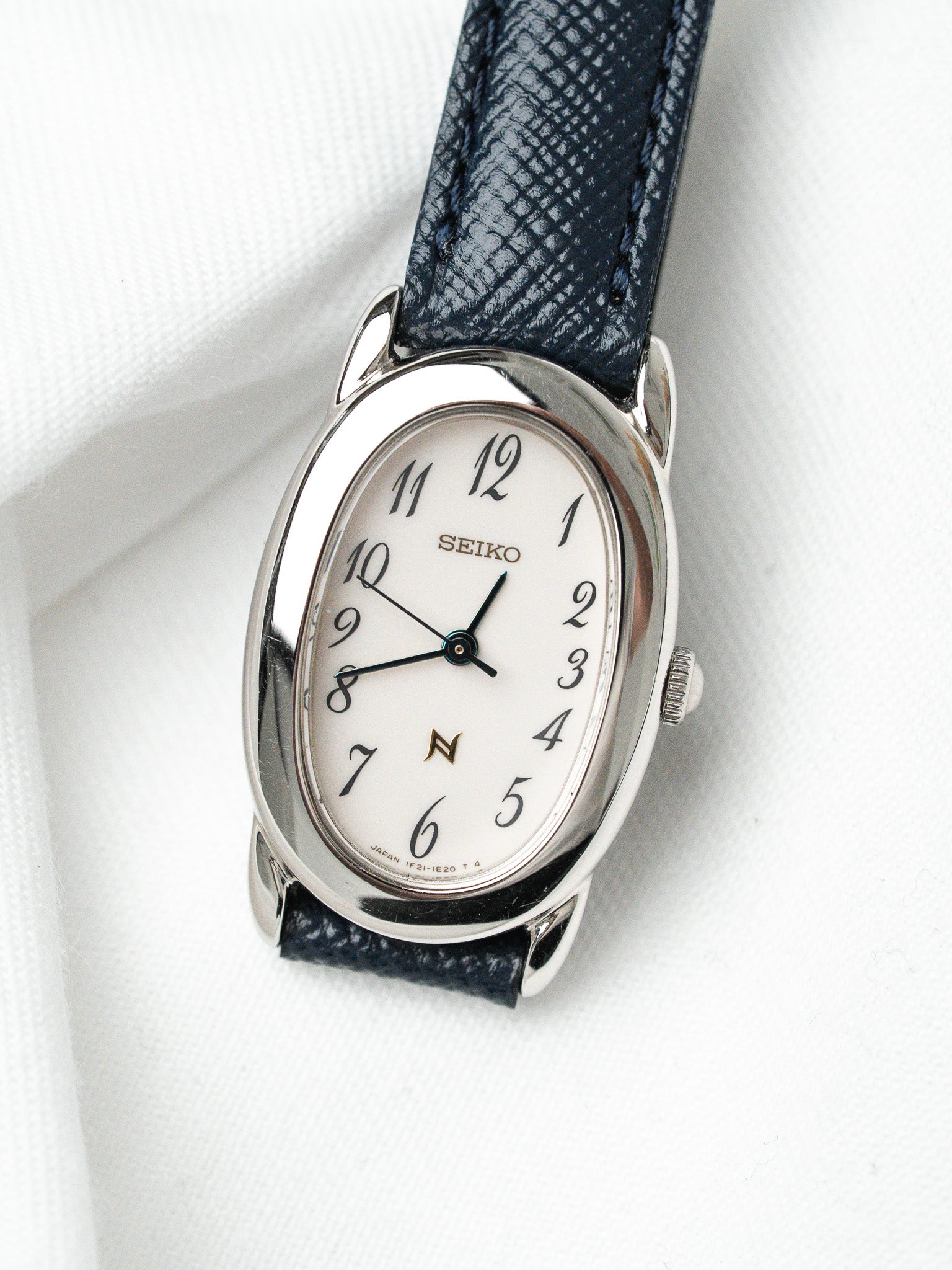Seiko vintage watch with white dial, steel case, and dark blue textured strap