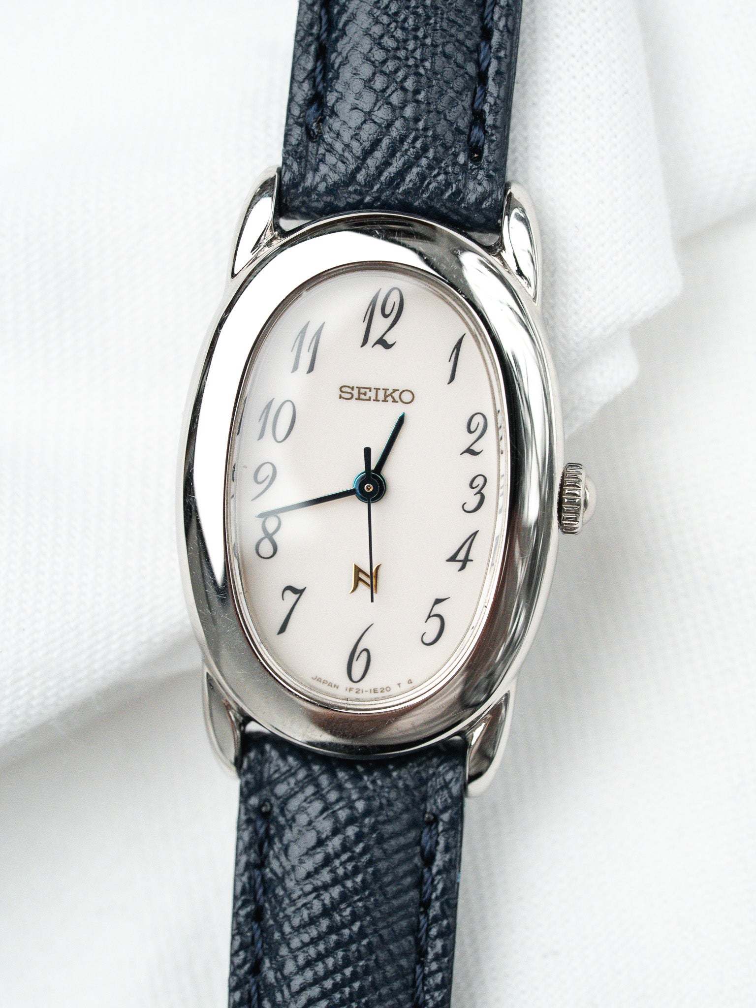 Seiko vintage watch with white dial, steel case, and dark blue textured strap