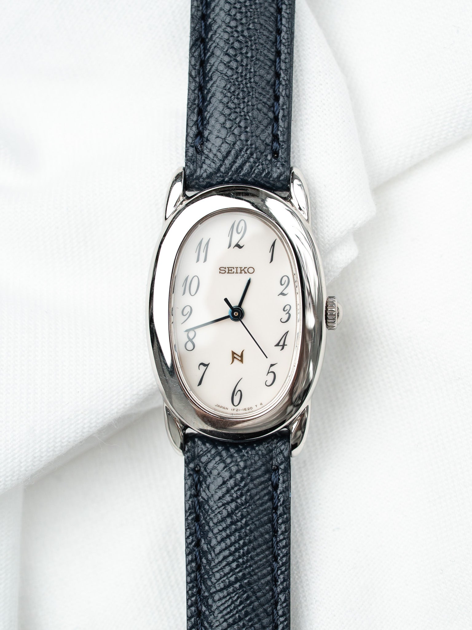 Seiko vintage watch with white dial, steel case, and dark textured leather strap