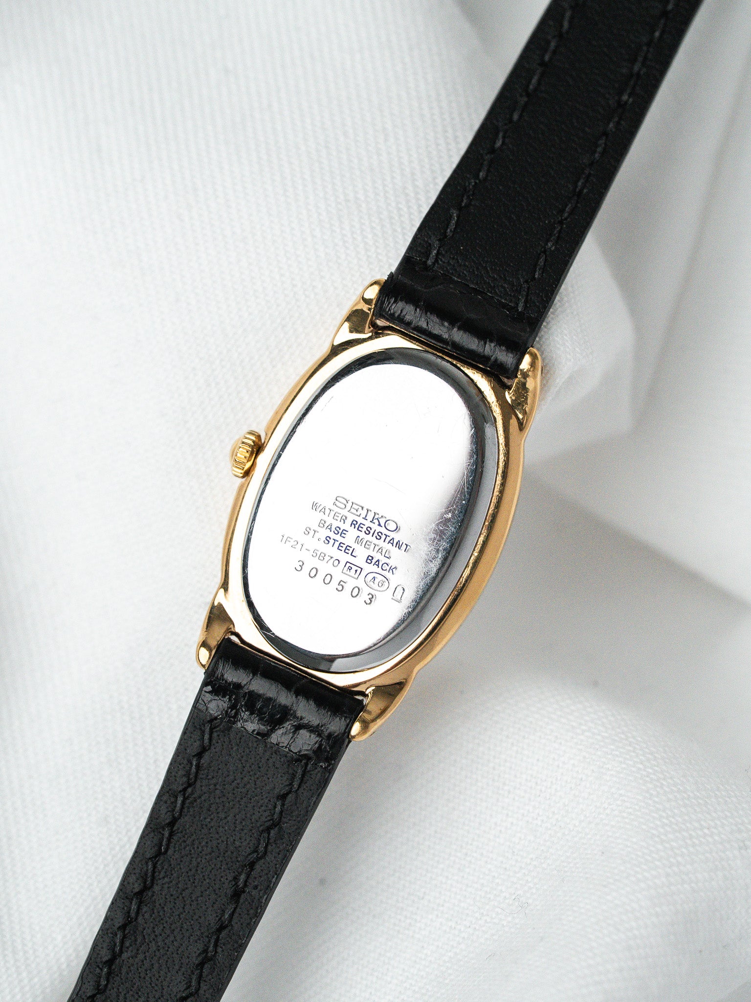 Seiko vintage watch with gold case, black leather strap, steel back visible