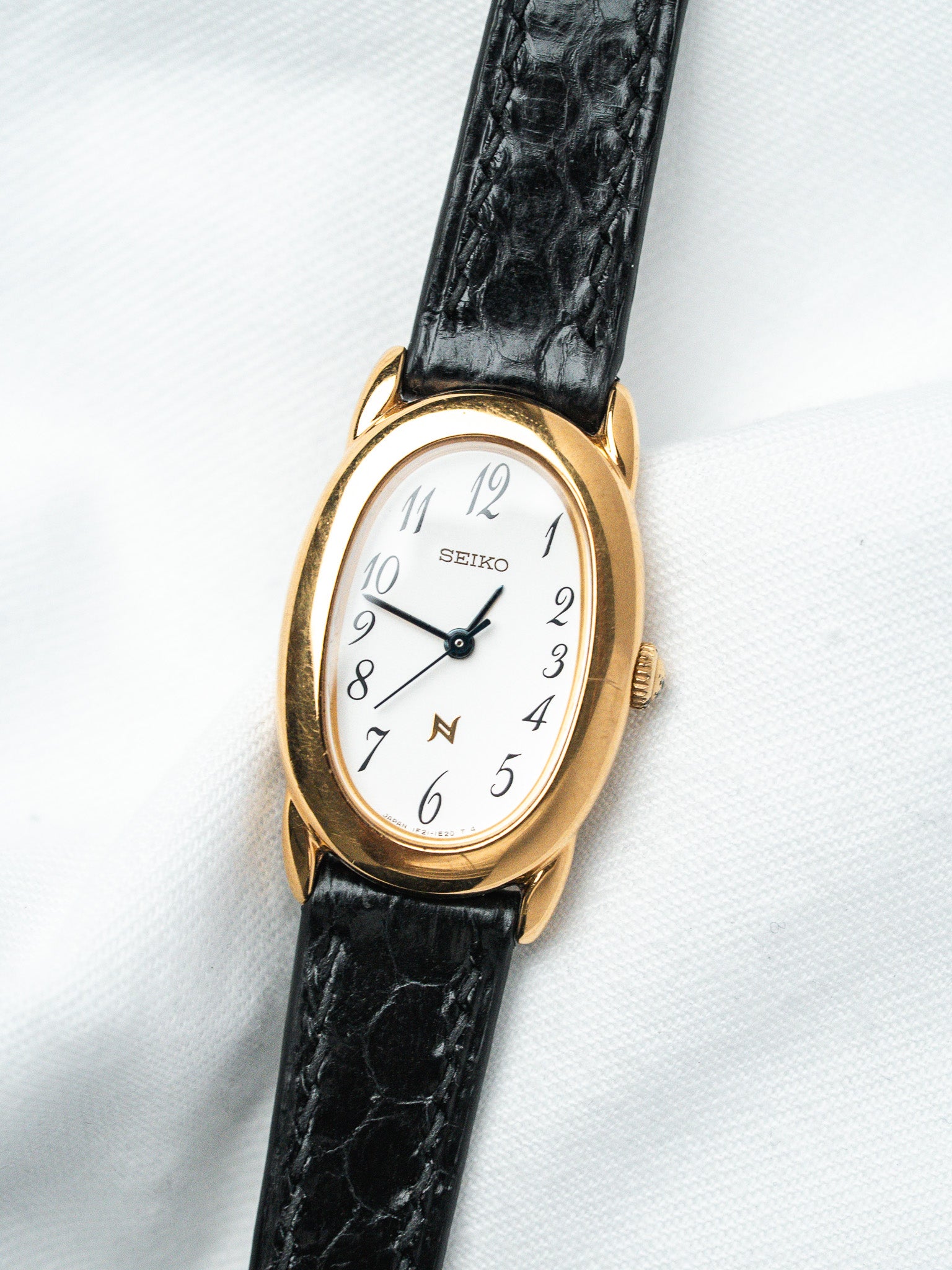 Seiko vintage watch with gold oval case, white dial, black leather strap