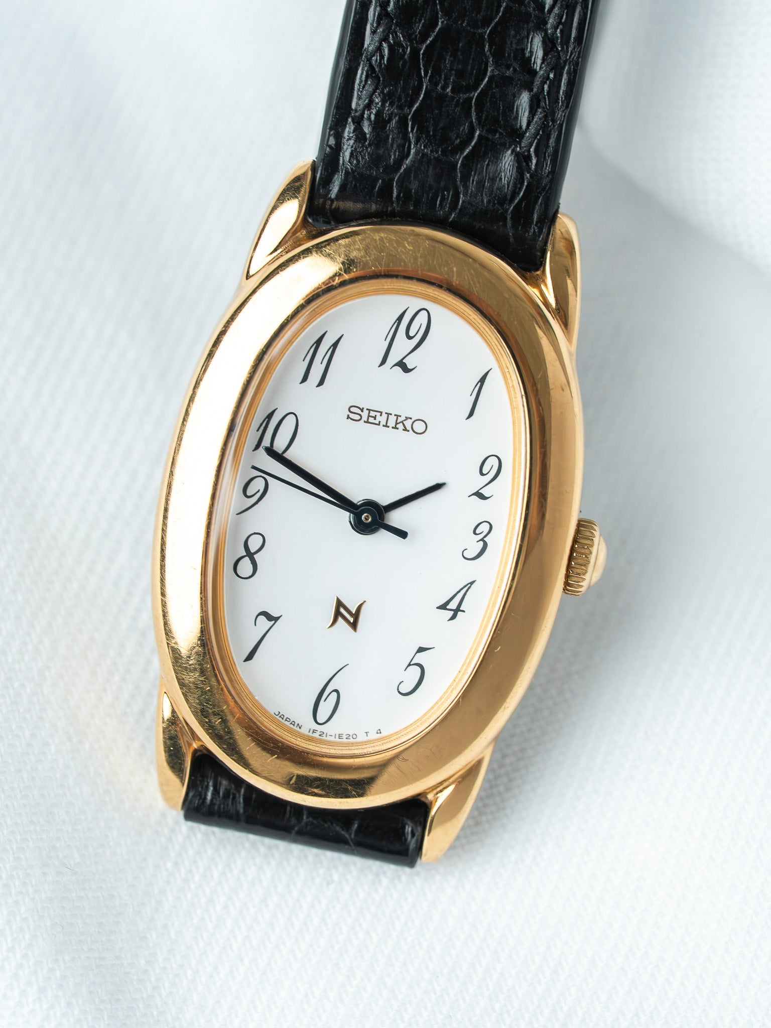 Seiko vintage watch with gold oval case, white dial, black leather strap