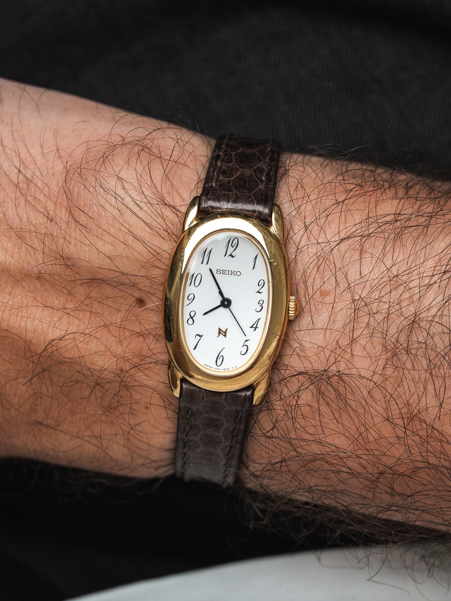 Seiko vintage watch with gold case, white dial, and brown leather strap on wrist