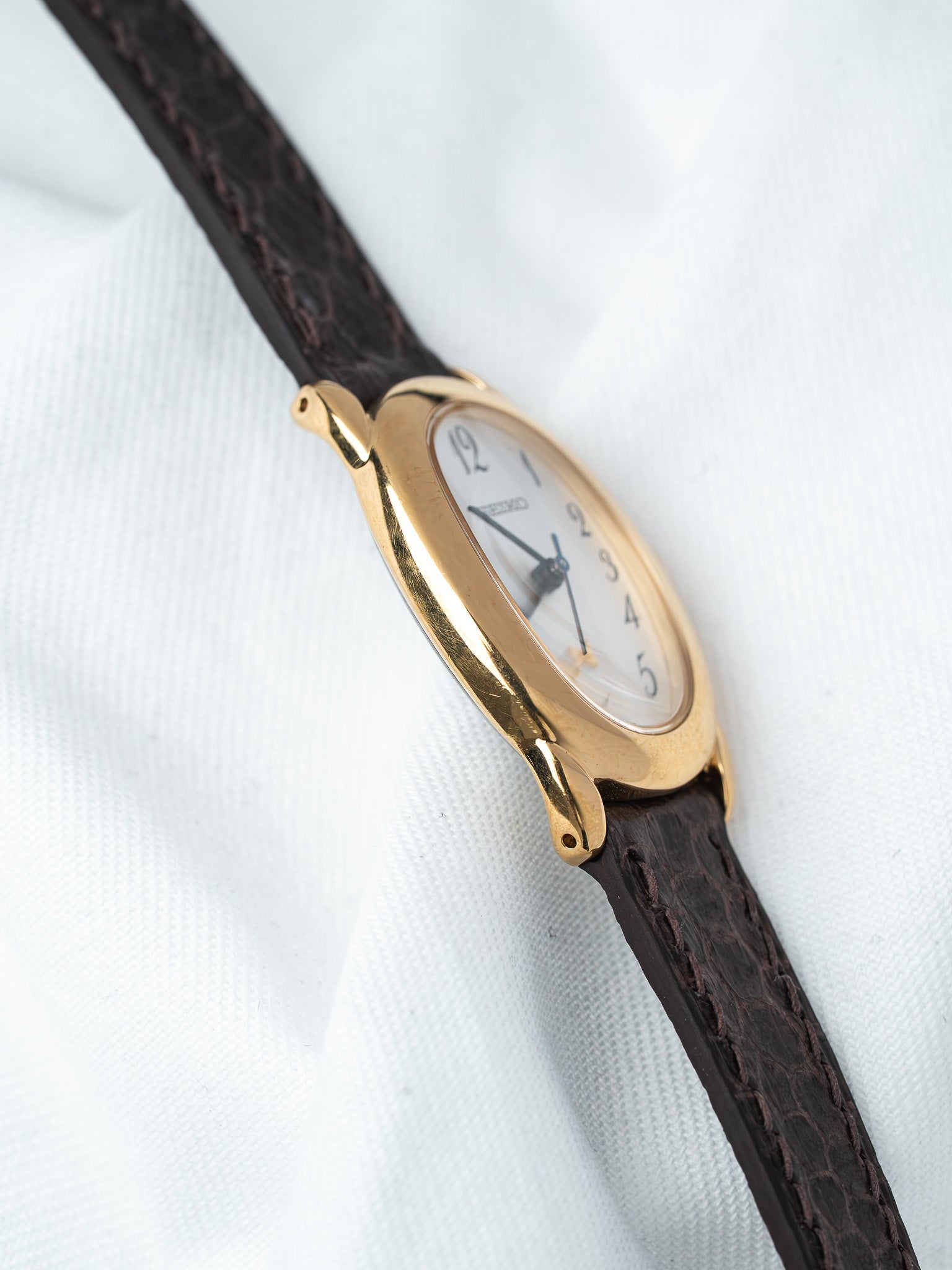 Cartier vintage watch with gold case, white dial, and brown leather strap
