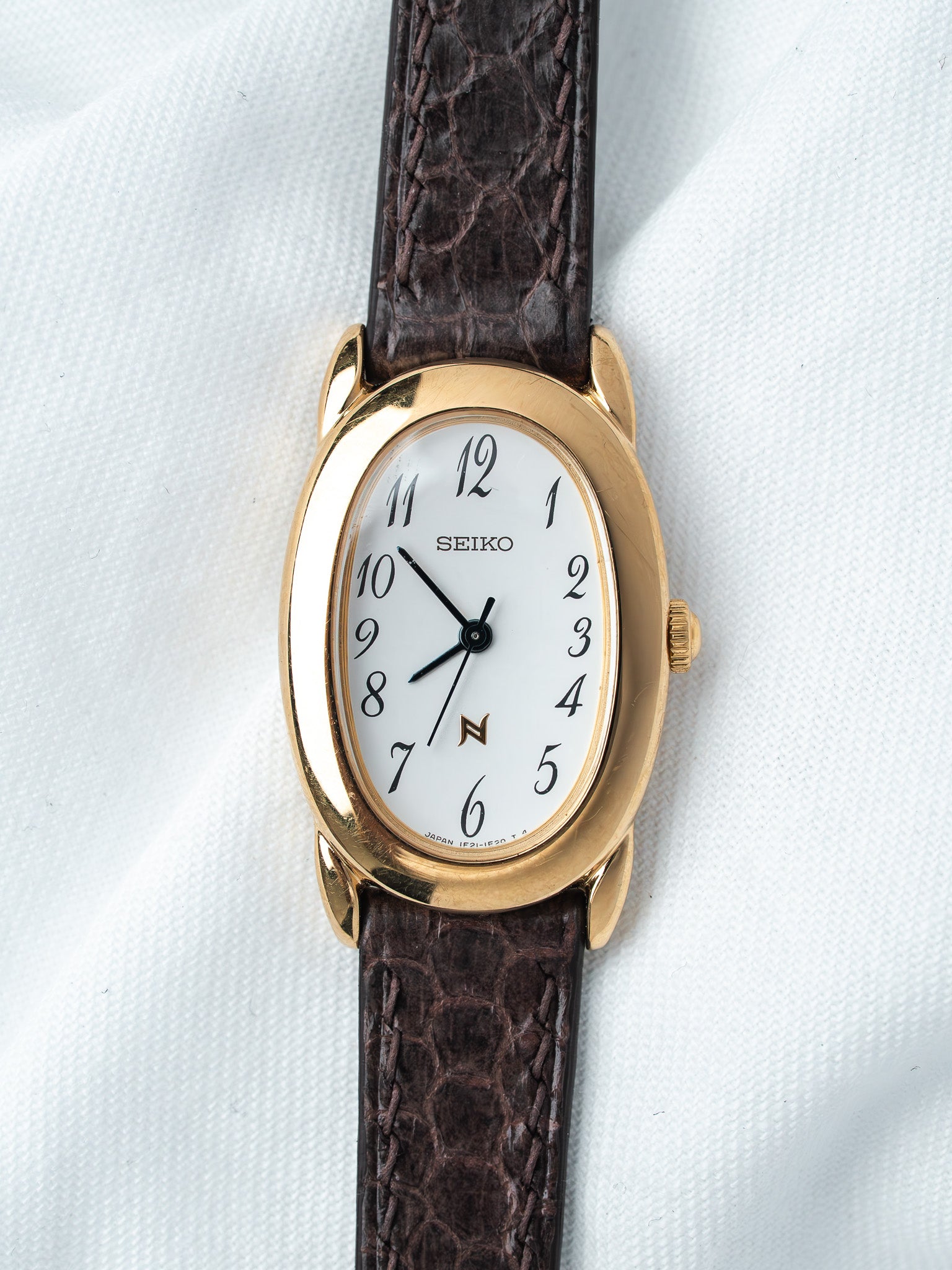Seiko vintage watch with gold case, white dial, and brown leather strap