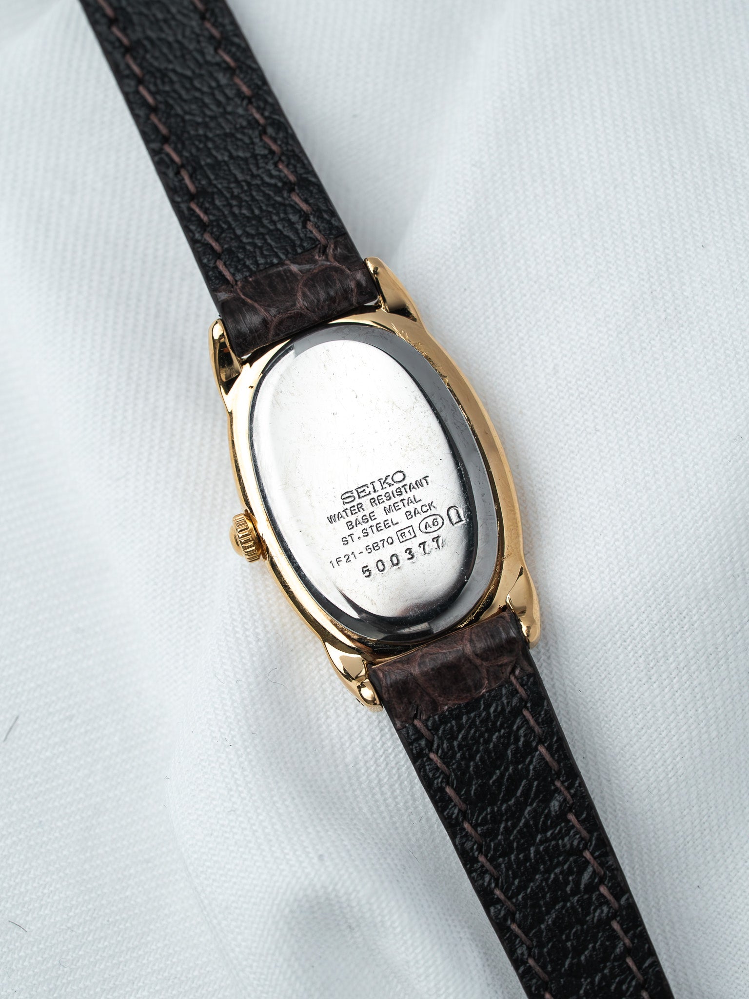 Seiko vintage watch with gold case, black leather strap, and stainless steel back