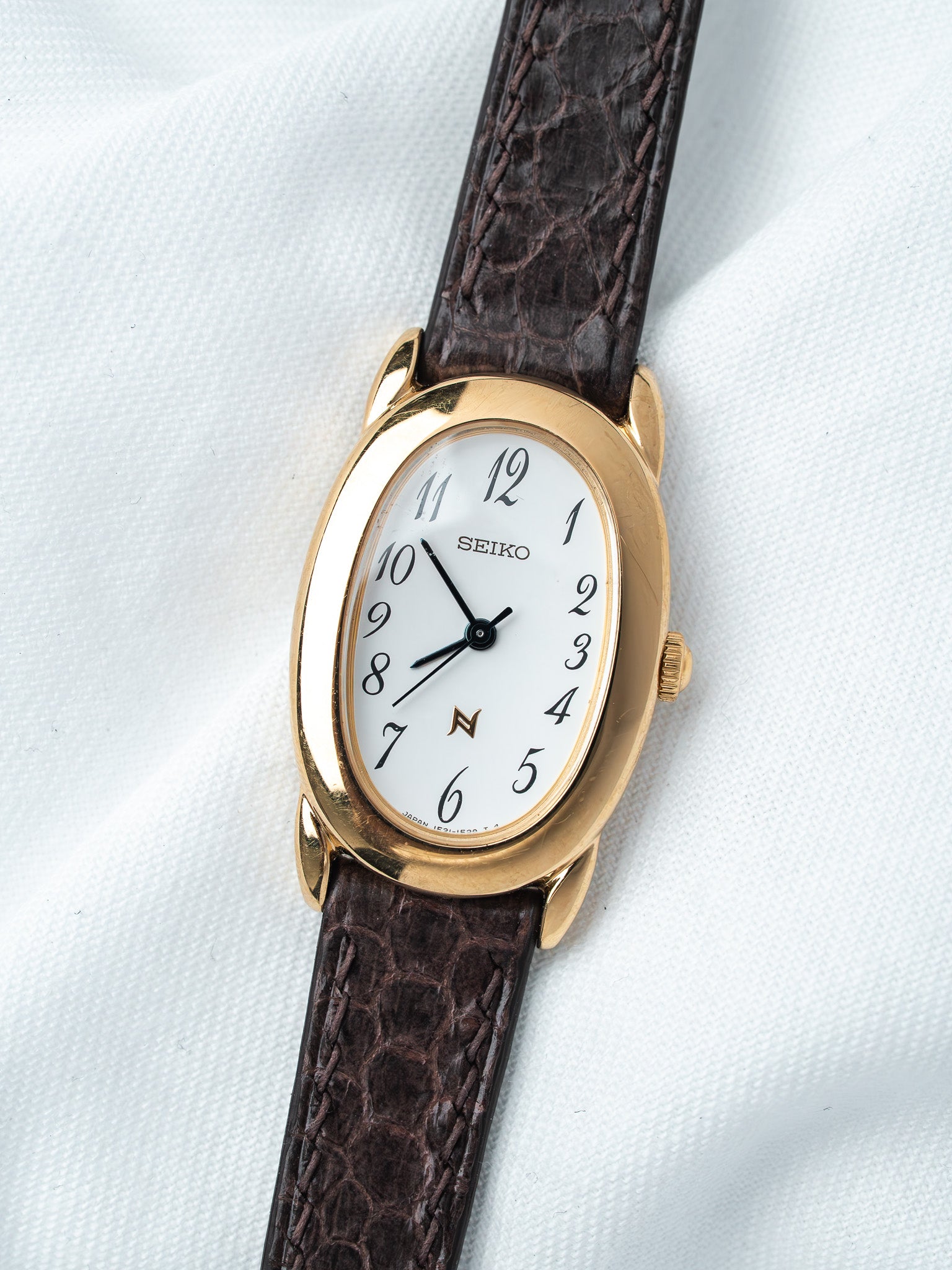 Seiko vintage watch with gold case, white dial, and brown leather strap