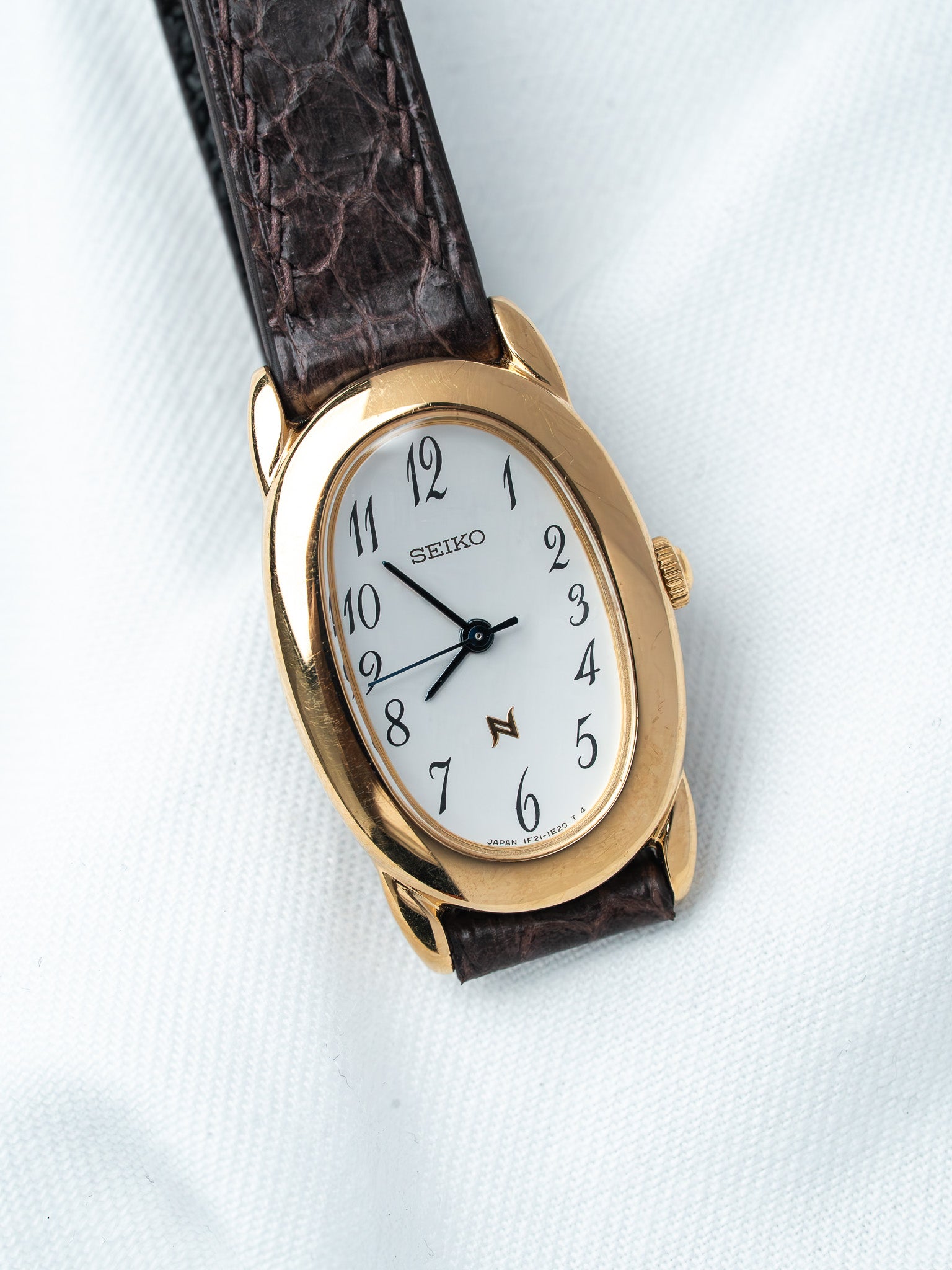 Seiko vintage watch with gold case, white dial, and brown leather strap