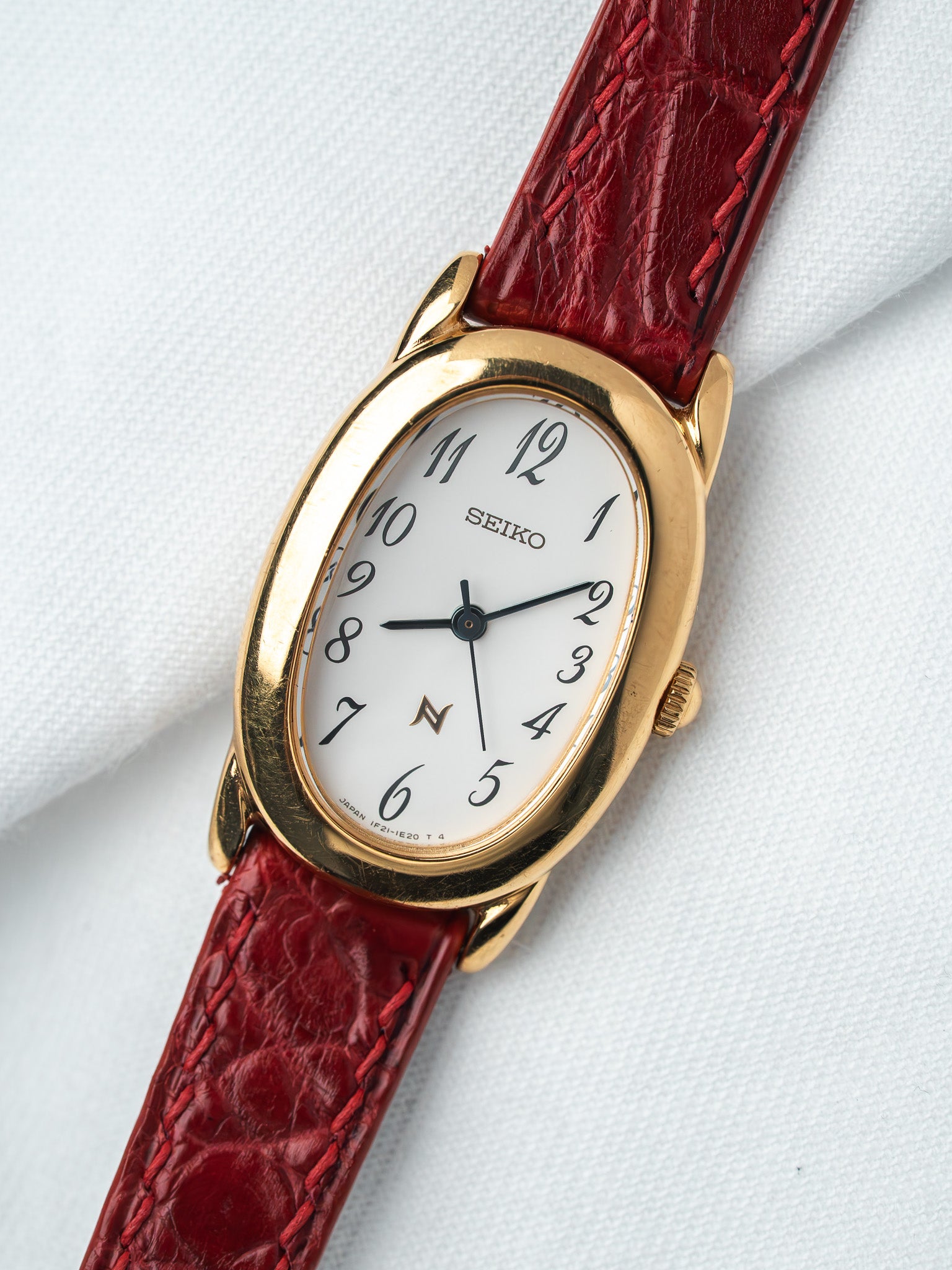 Seiko vintage watch with gold case, white dial, and red alligator strap