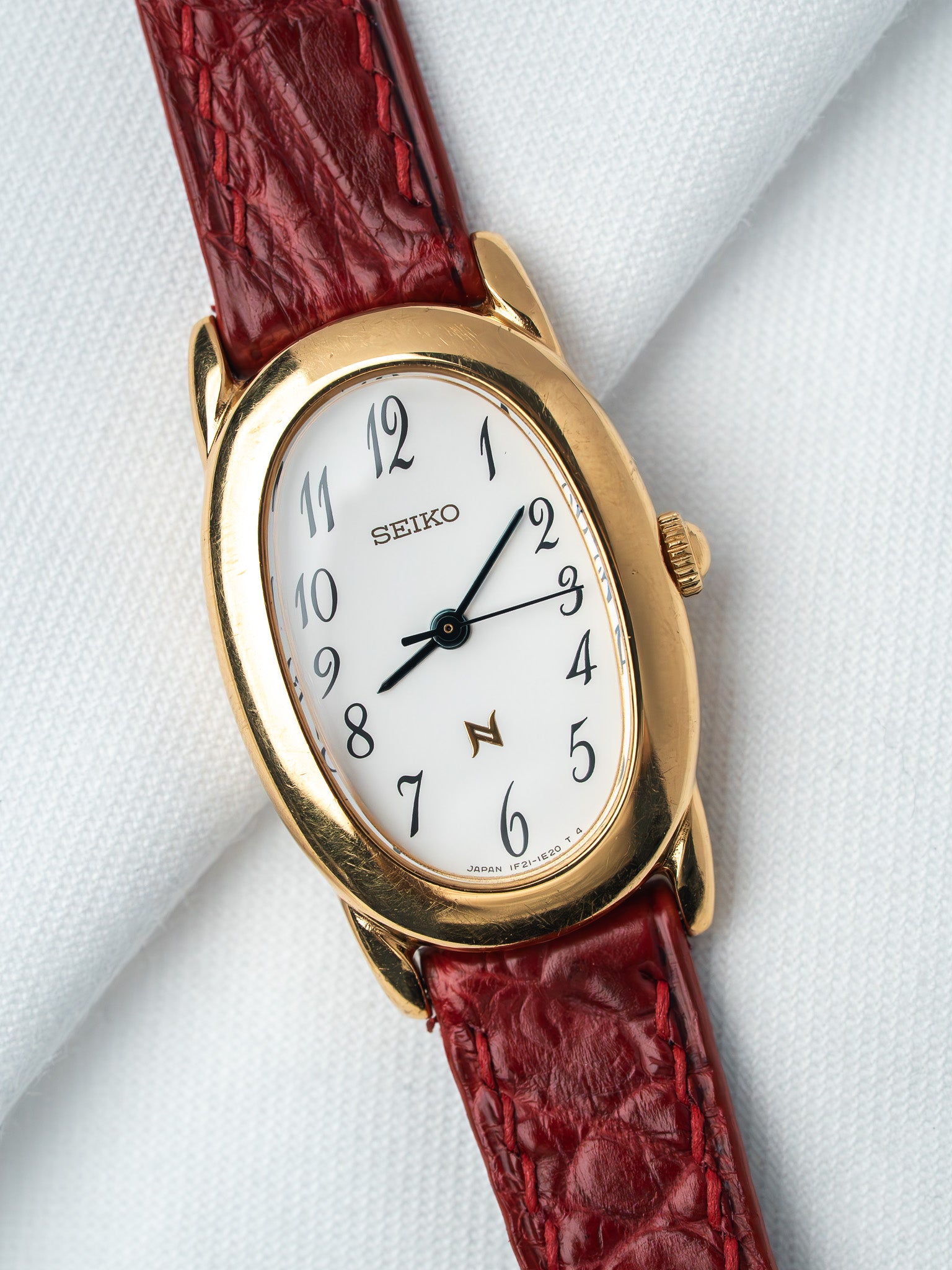 Seiko vintage watch with gold case, white dial, and red leather strap