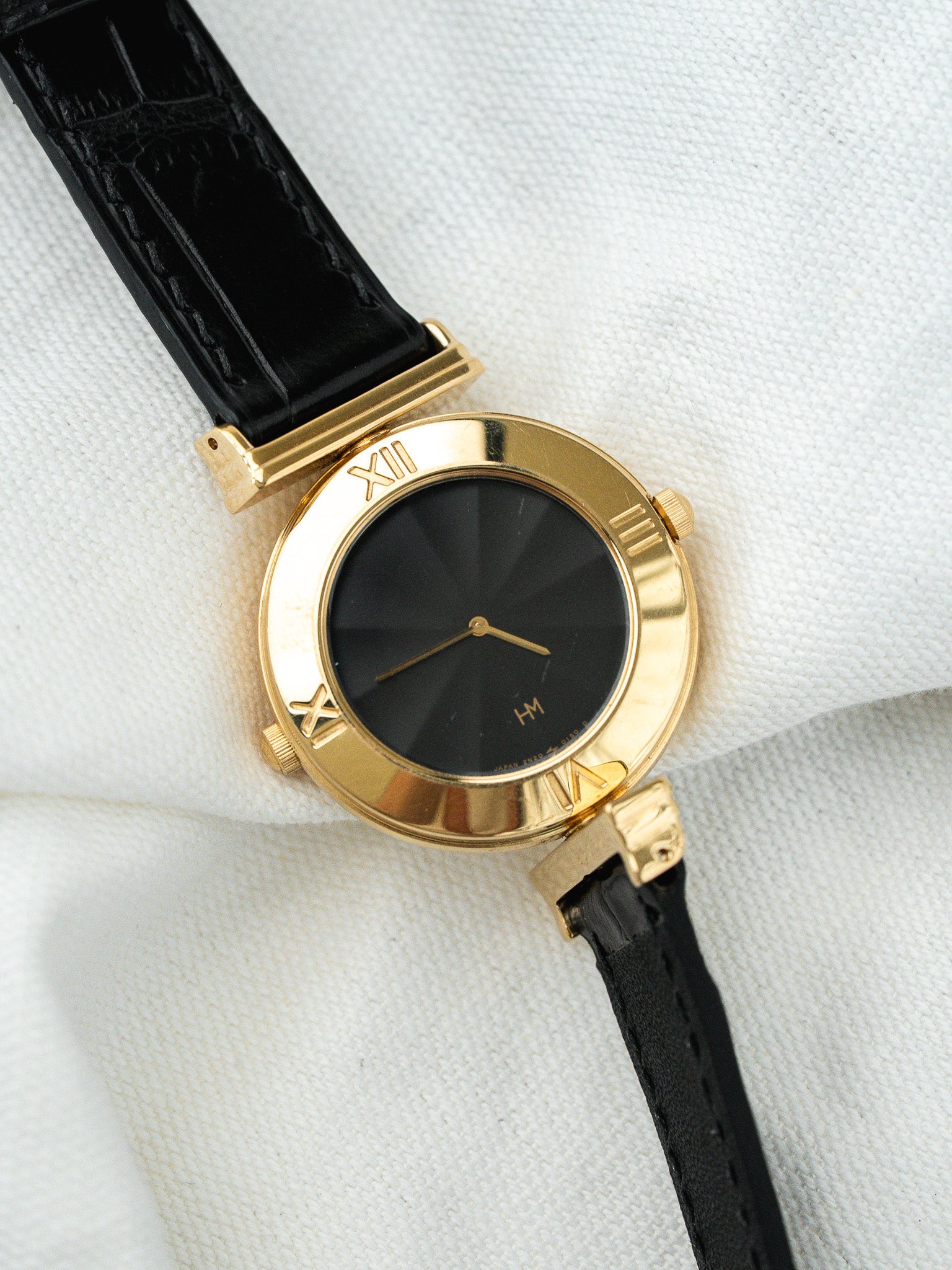 Vintage HM watch with gold case, black sunburst dial, Roman numerals, black leather strap