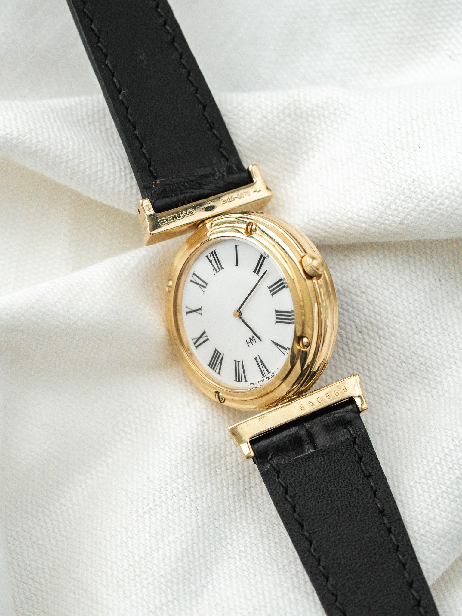 Seiko vintage watch with gold case, white dial, Roman numerals, black leather strap