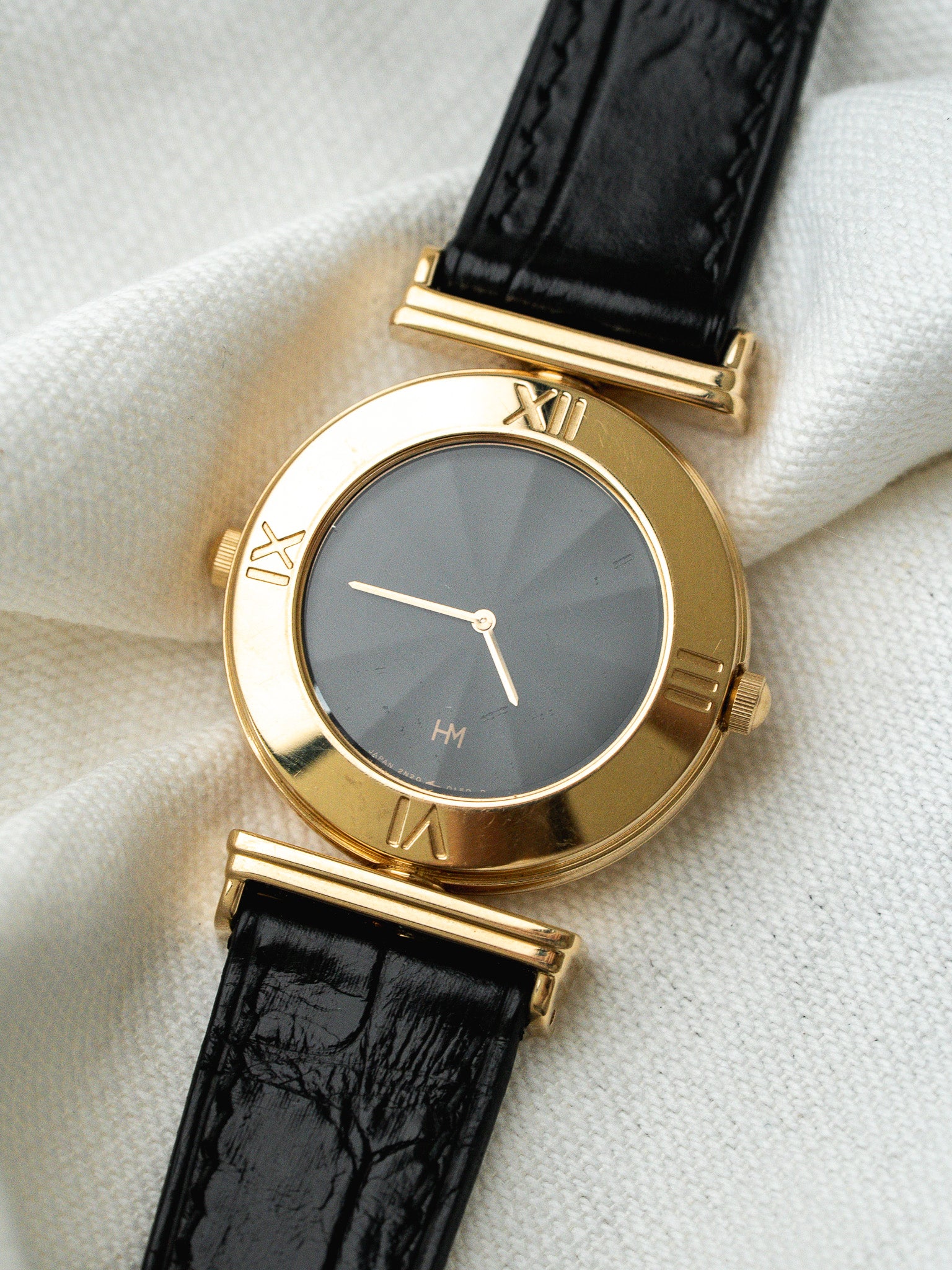 Montre HM vintage en or jaune, cadran gris, bracelet cuir noir texturé