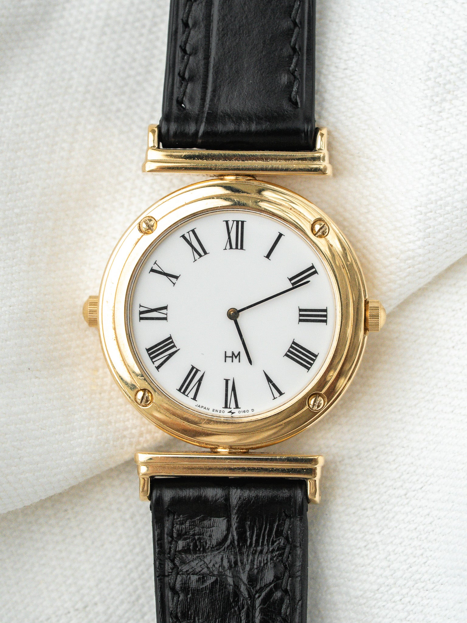 Montre HM vintage en or jaune, cadran blanc chiffres romains, bracelet cuir noir