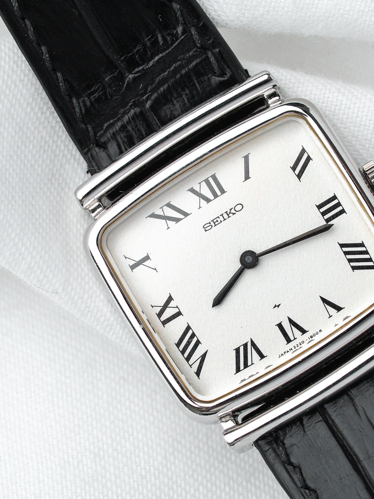 Seiko vintage watch with silver case, white dial, Roman numerals, black leather strap