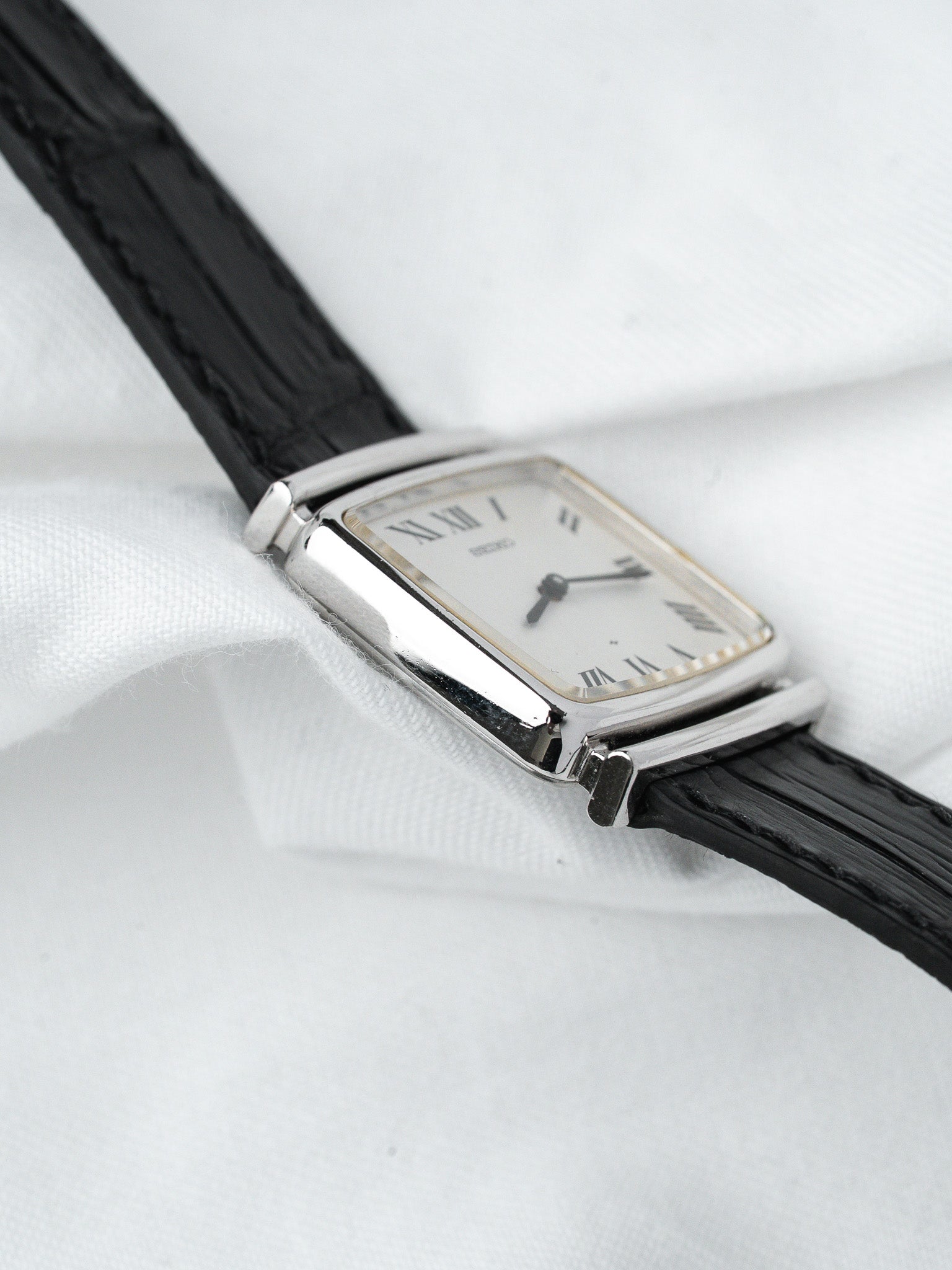 Cartier vintage watch with rectangular case, white dial, Roman numerals, black leather strap