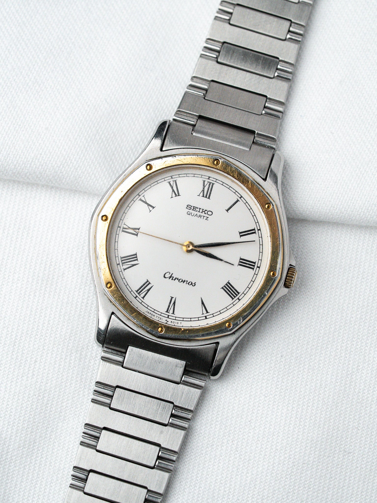 Seiko Chronos vintage quartz watch with white dial, Roman numerals, gold bezel, steel bracelet