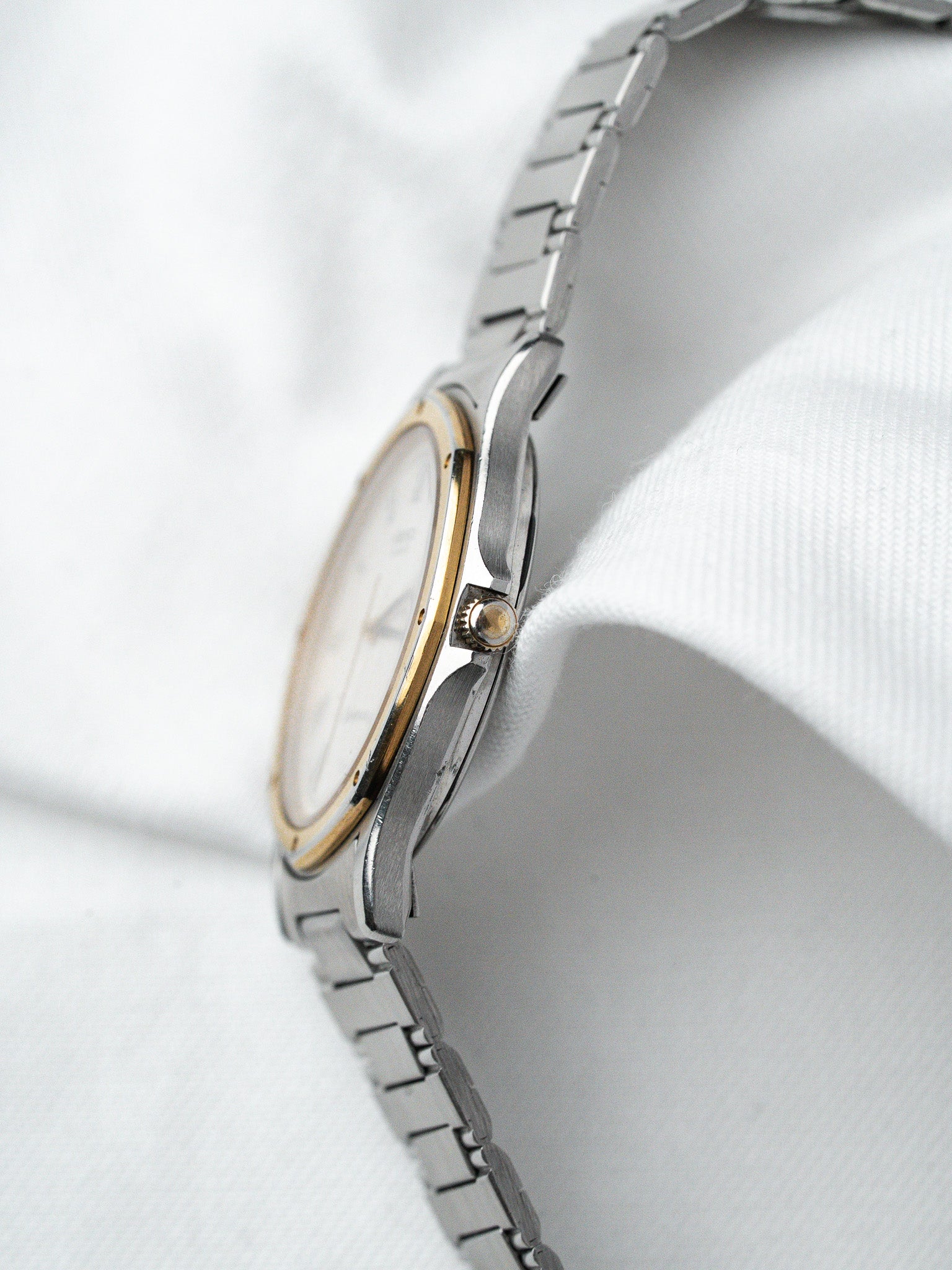 Vintage Omega watch with two-tone steel and gold case, white dial, on white fabric