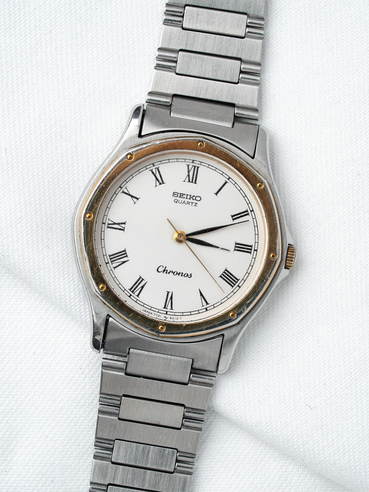 Seiko Chronos vintage quartz watch with white dial, Roman numerals, steel bracelet on white background
