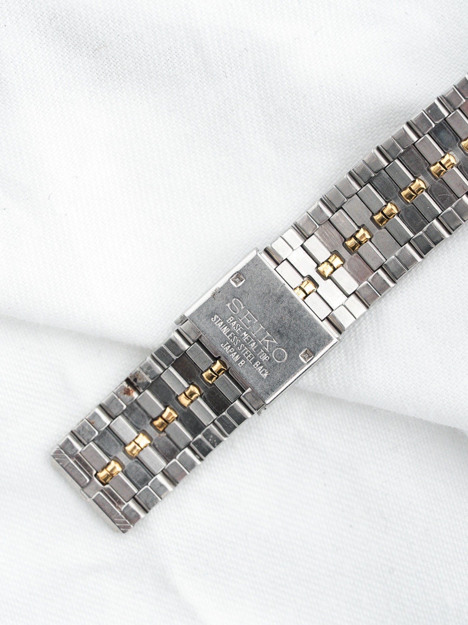 Seiko vintage watch bracelet with two-tone stainless steel and gold accents on white background