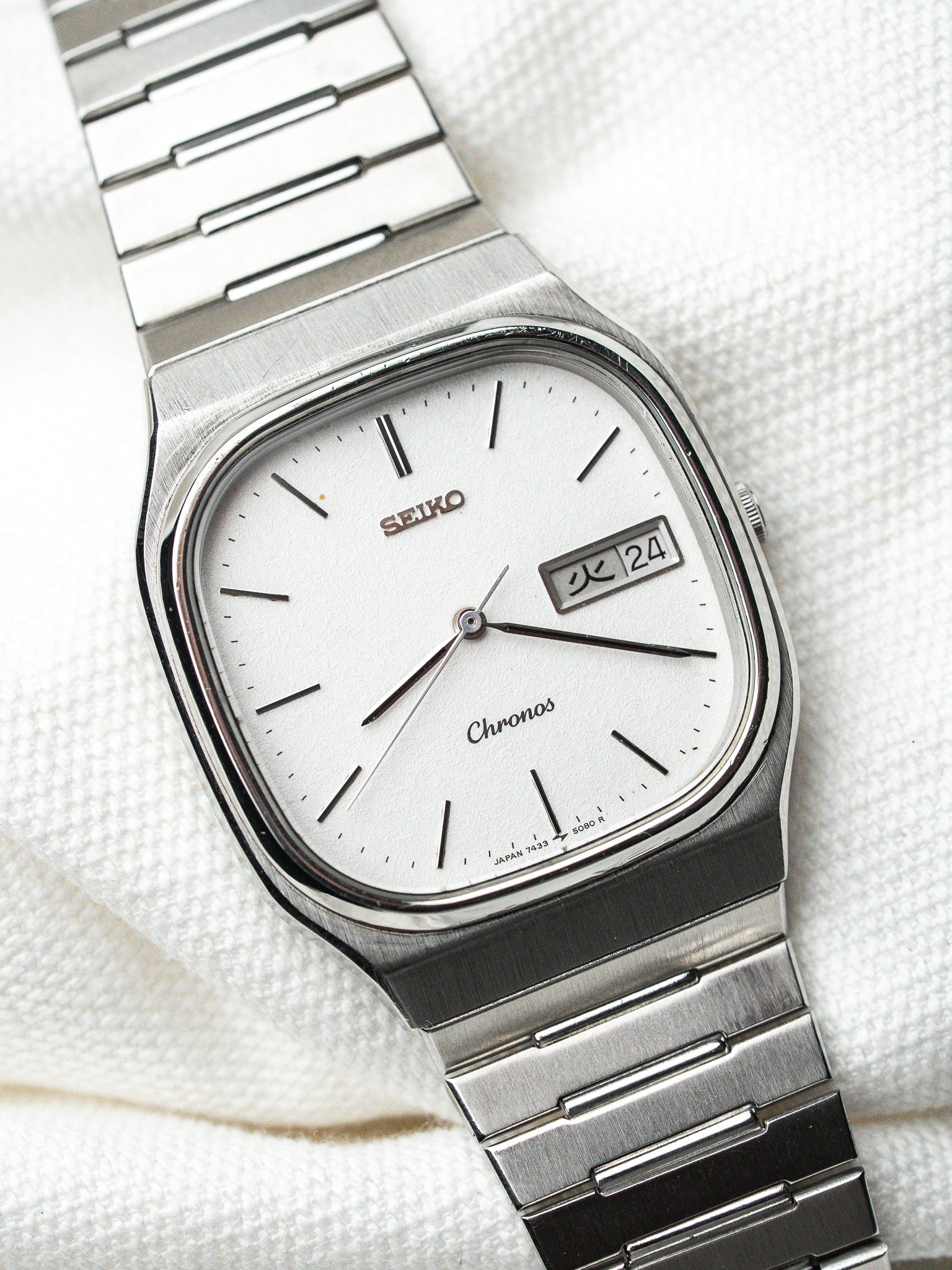 Seiko Chronos vintage watch with silver dial, day-date window, and steel bracelet on white fabric