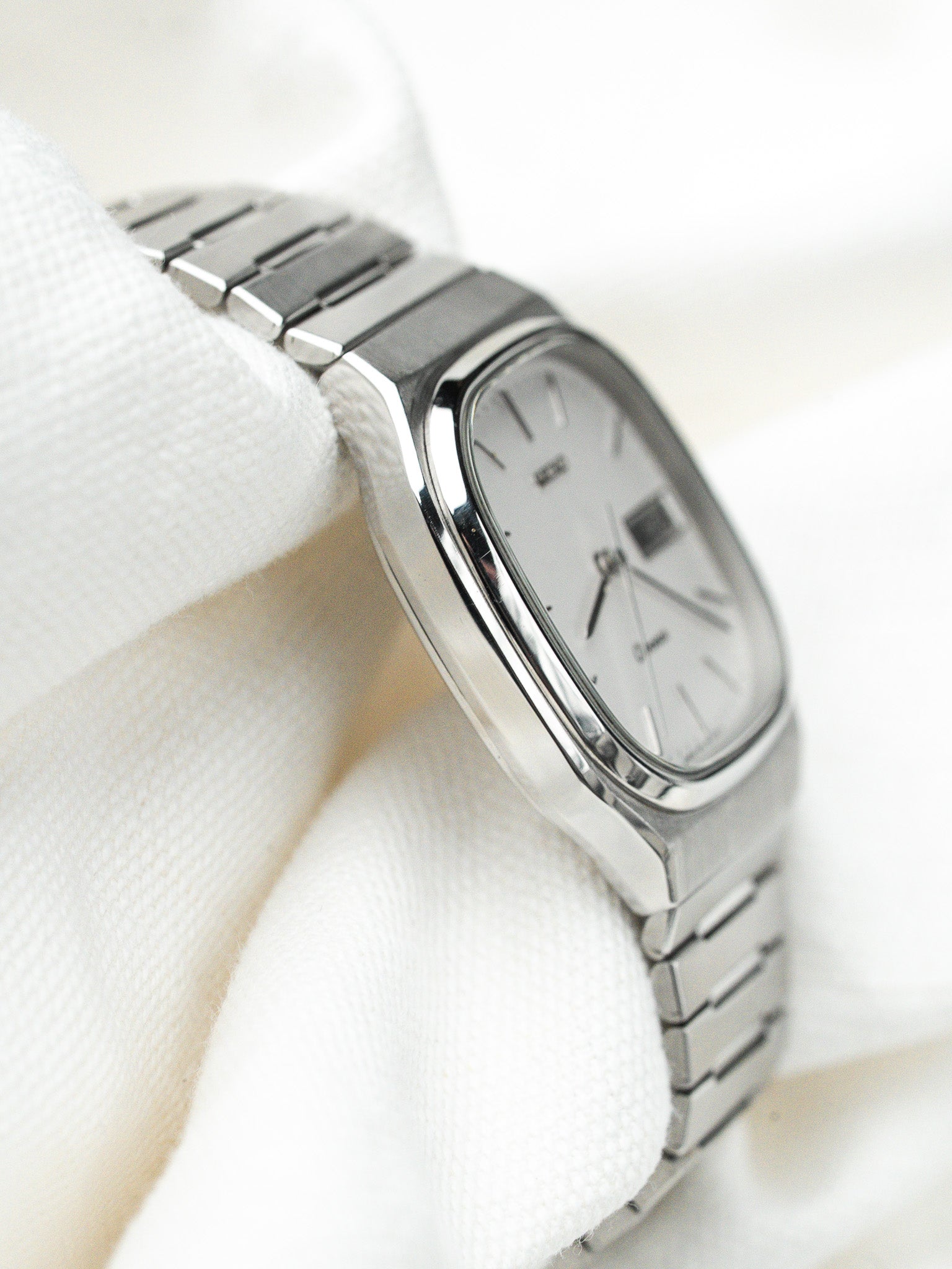 Omega vintage watch with silver dial, steel case and bracelet, displayed on white fabric
