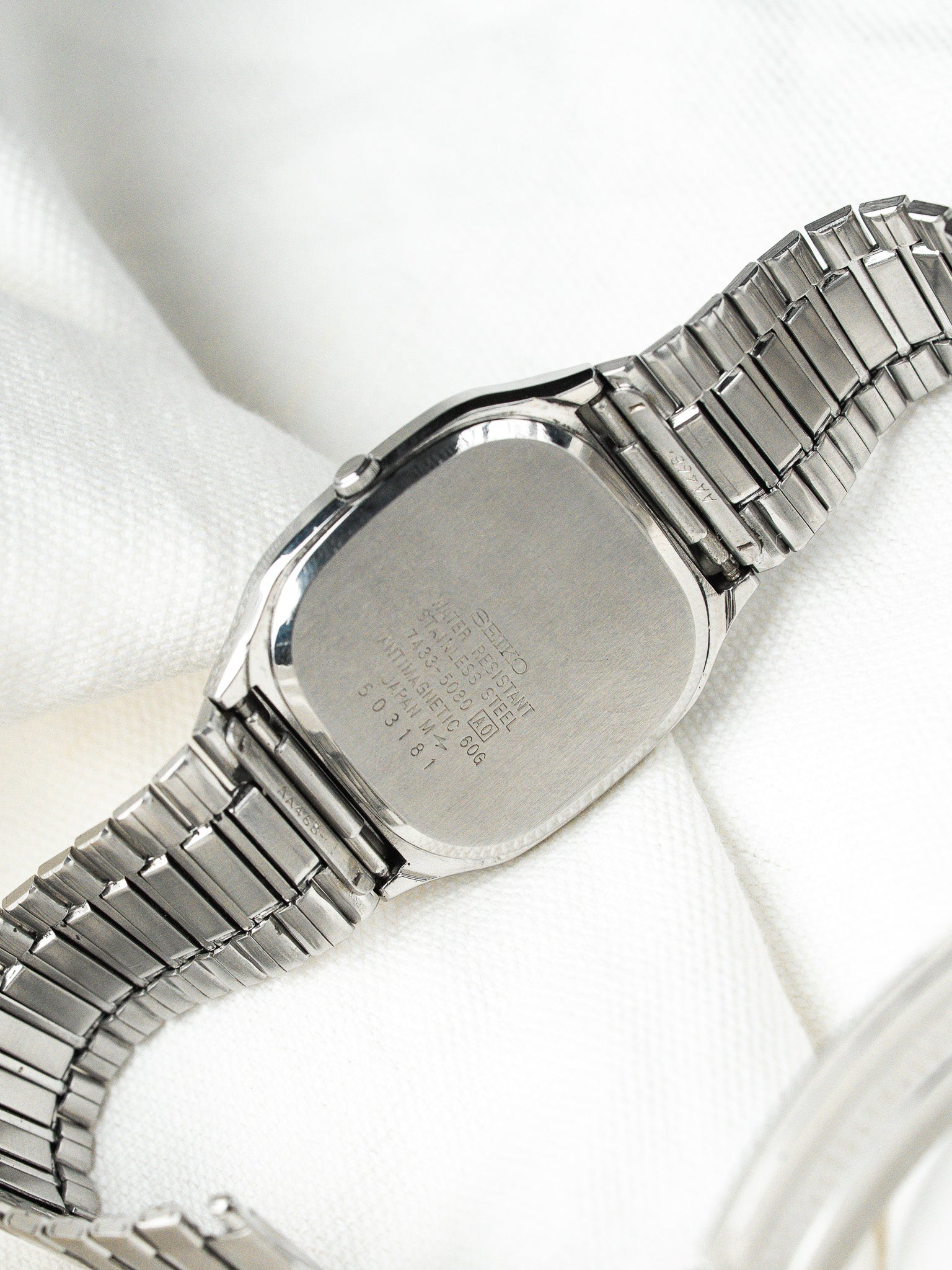 Seiko vintage watch back stainless steel case with engraved details on white fabric
