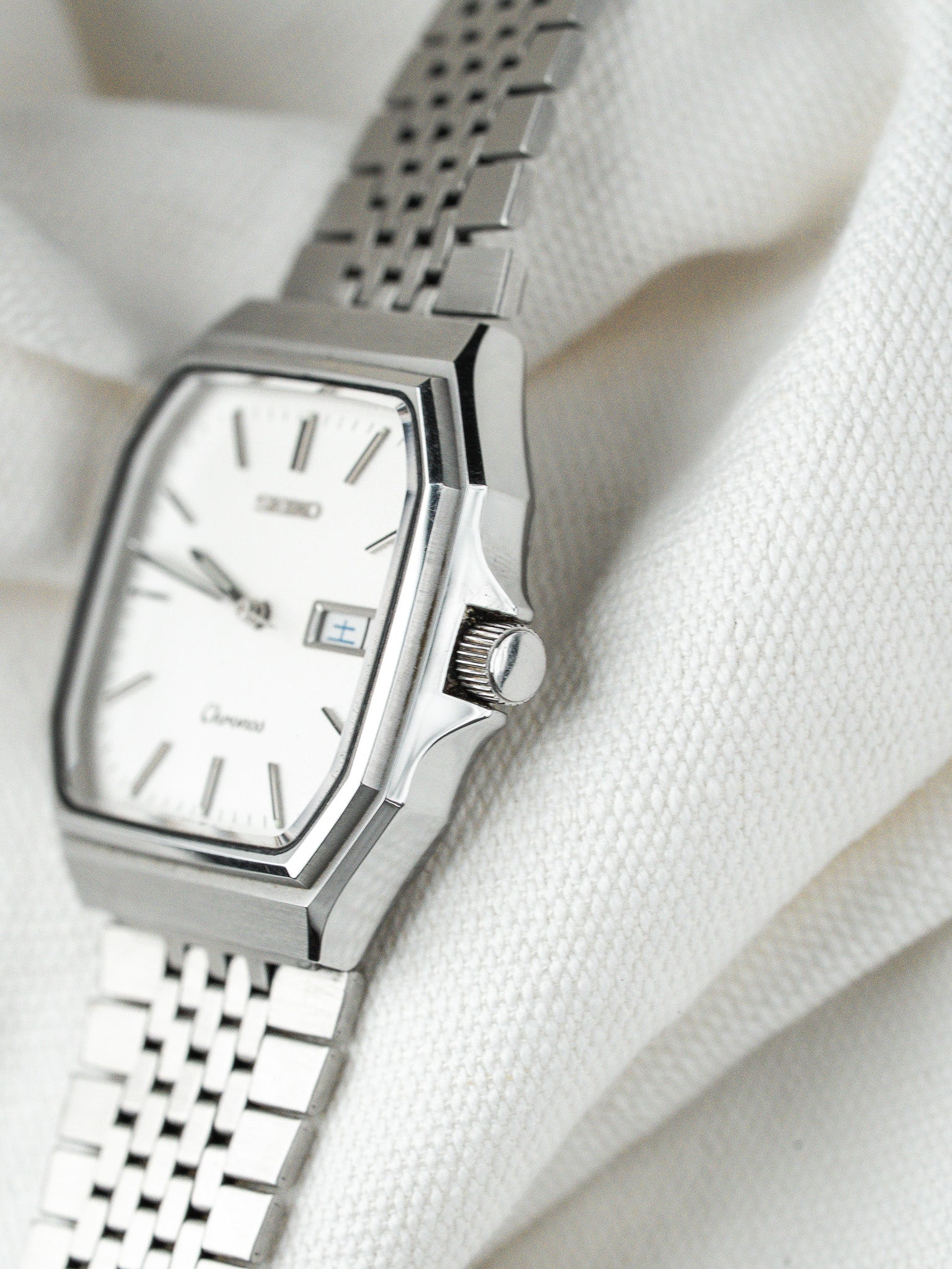Seiko Chronos vintage watch with white dial, steel case, and mesh bracelet on fabric
