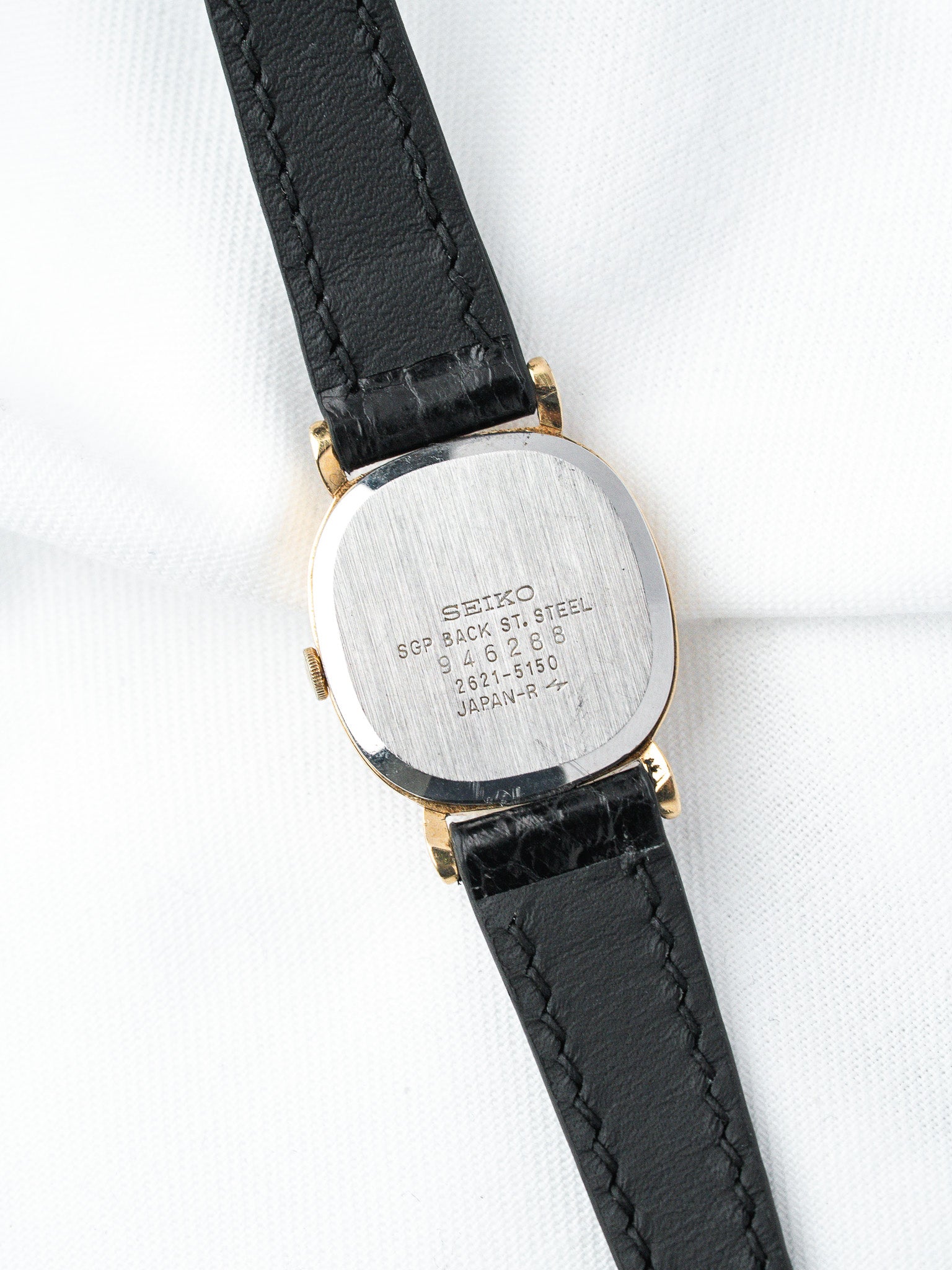 Seiko vintage watch with gold case, black leather strap, steel back engraved